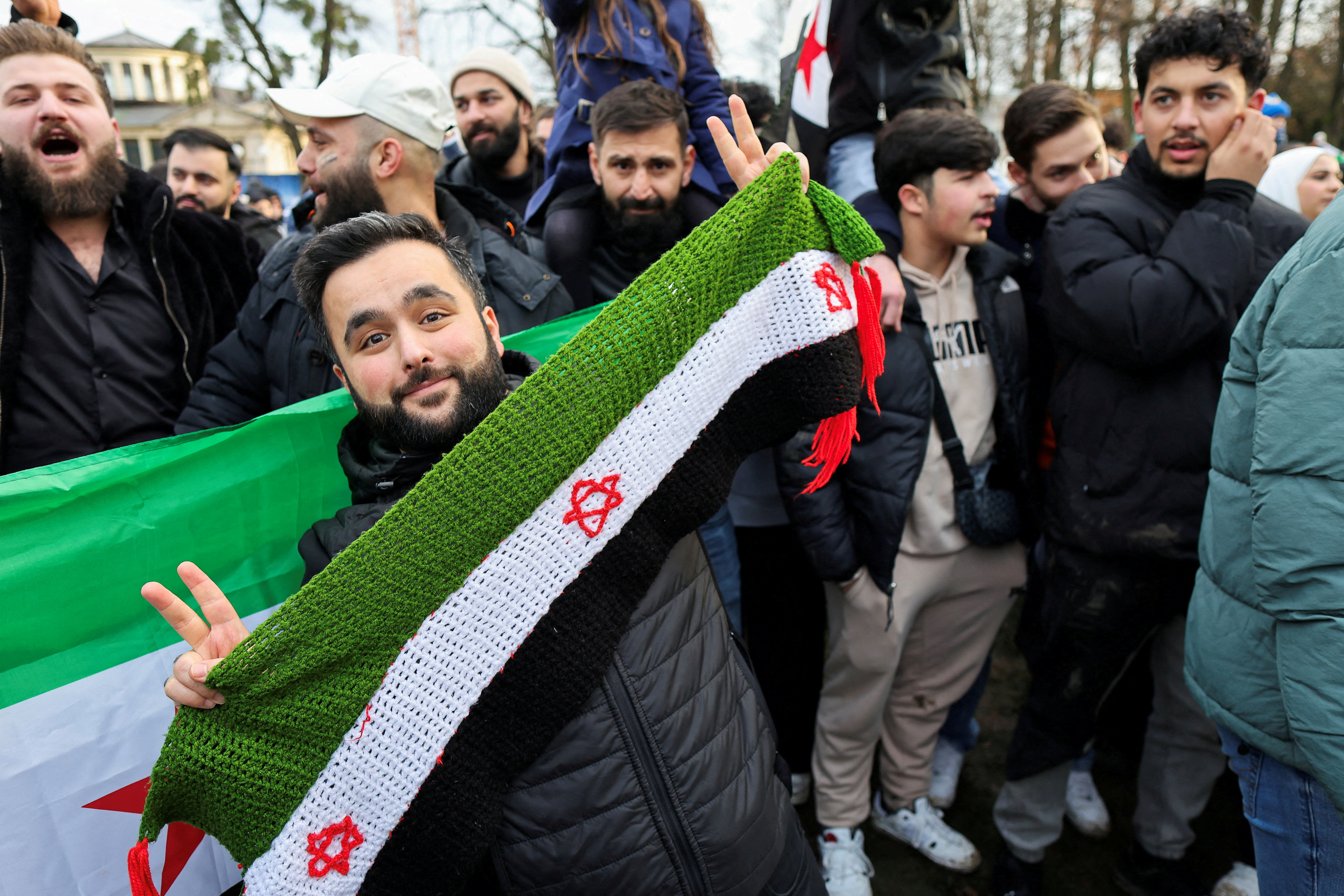 A man holds a representation of the Syrian opposition flag