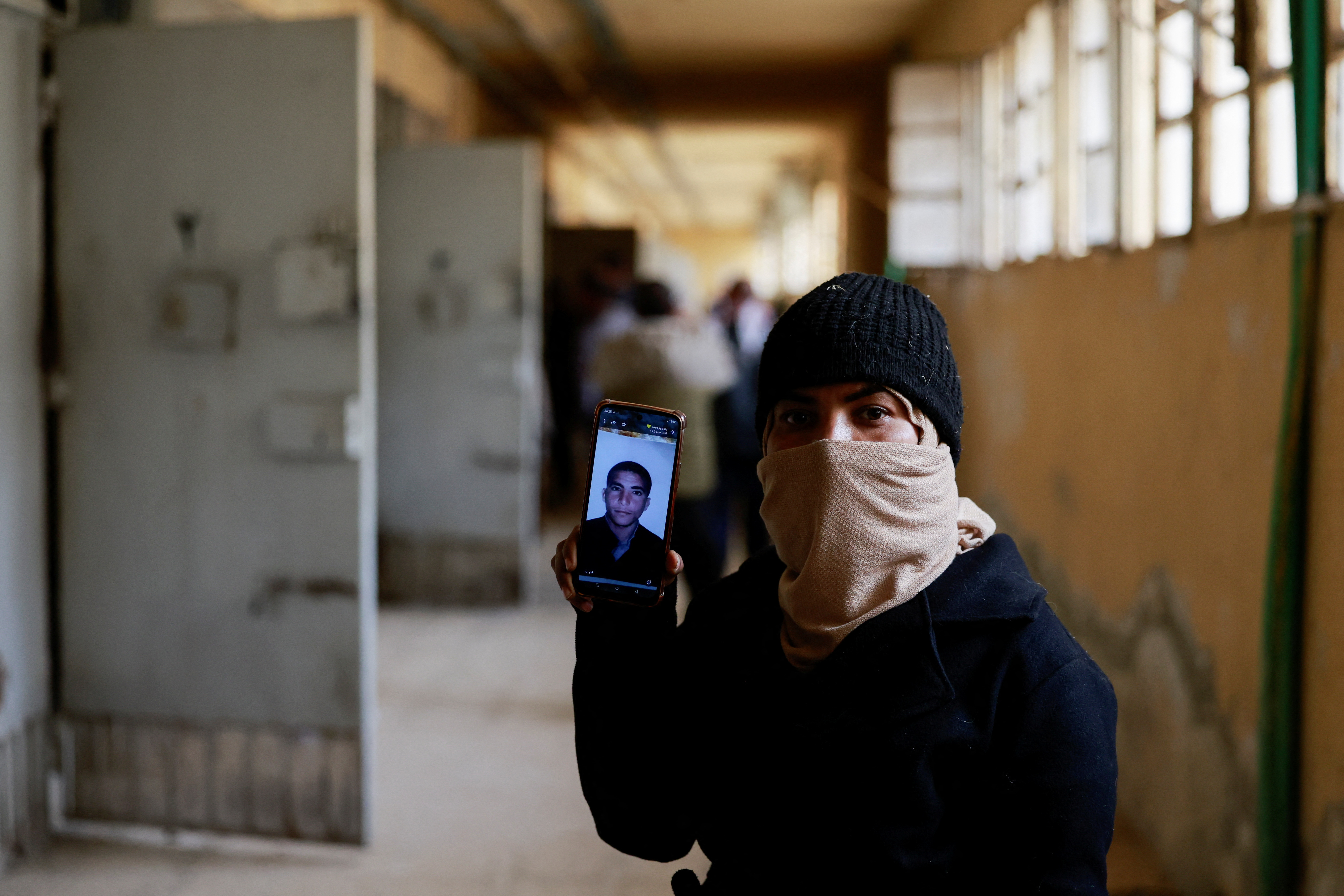 Hayat al-Turki, 27, holds a phone with the picture of her brother at Sednaya prison, which was known as a slaughterhouse under Syria's Bashar al-Assad rule, as she searches the prison in the hope of finding her relatives, after rebels seized the capital and announced that they have ousted Syria's Bashar al-Assad, in Sednaya, Syria, December 11, 2024. REUTERS/Ammar Awad