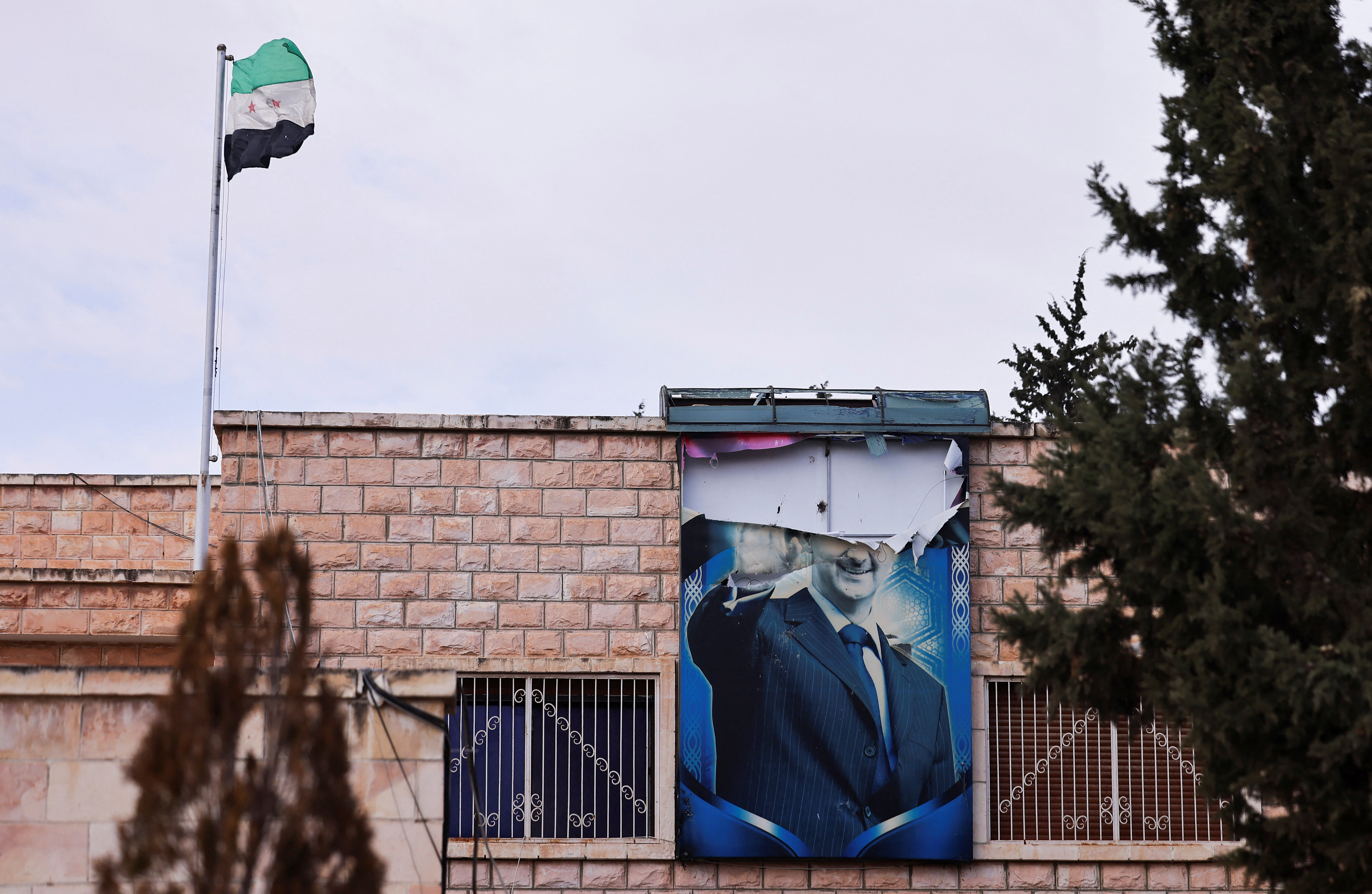 A torn poster of Syria's ousted President Bashar al-Assad hangs on a building