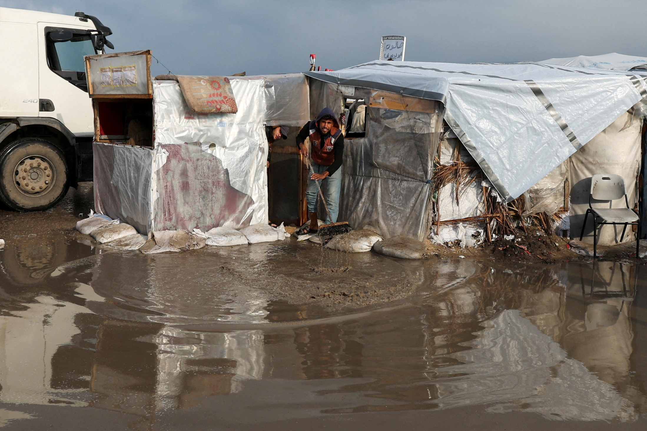 A displaced Palestinian man removes water at a tent camp, following heavy rains, amid the Israel-Hamas conflict, in Deir Al-Balah, in the central Gaza Strip, December 30