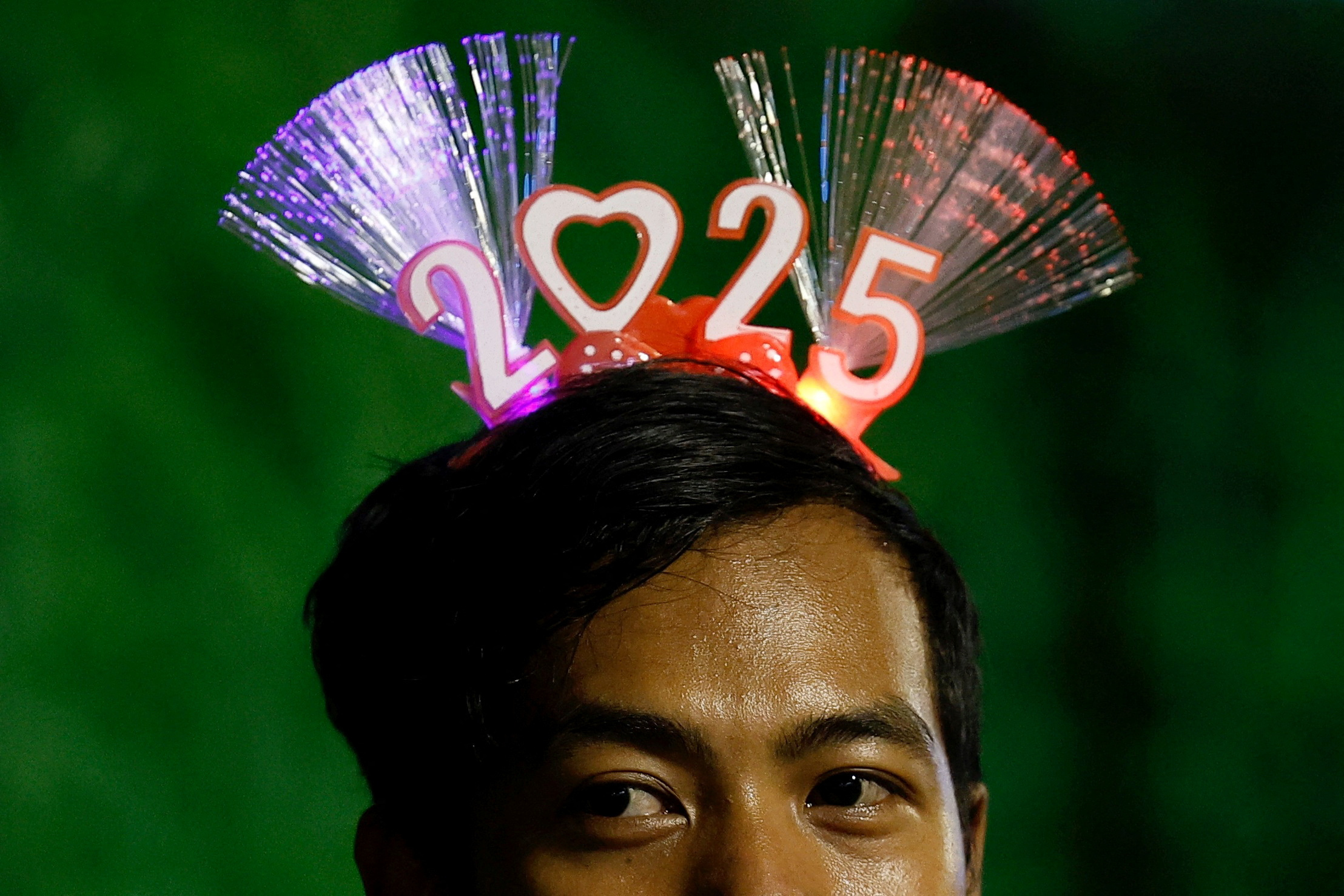 A man wearing '2025' head band attends the New Year's Eve celebrations in Jakarta, Indonesia, December 31