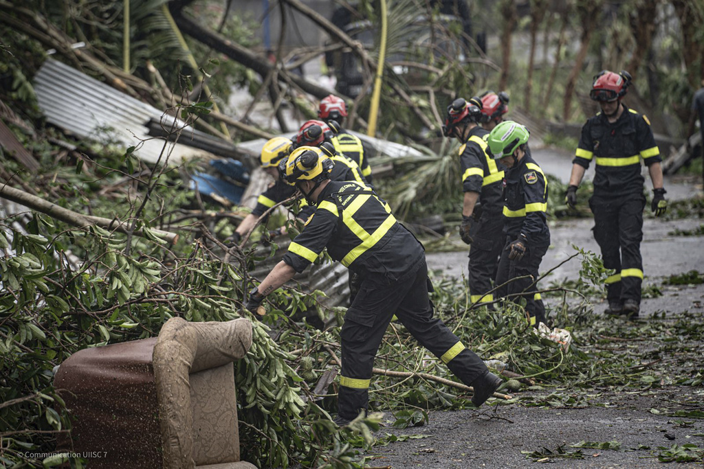 This photo provided on Monday Dec. 16, 2024 by the Civil Security shows rescue workers clearing a street in French territory of Mayotte in the Indian Ocean, after the island was battered by its worst cyclone in nearly a century. (UIISC7/Securite Civile via AP)