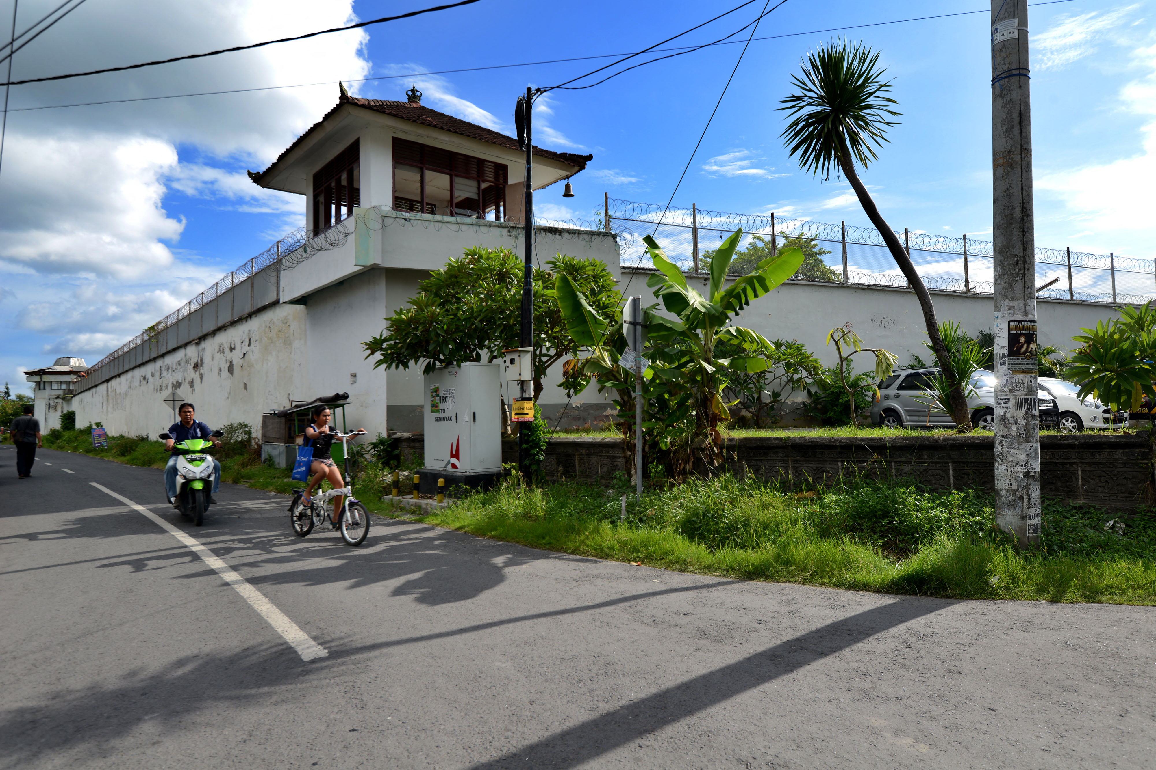 Motorists ride past the exterior of the notorious Kerobokan prison