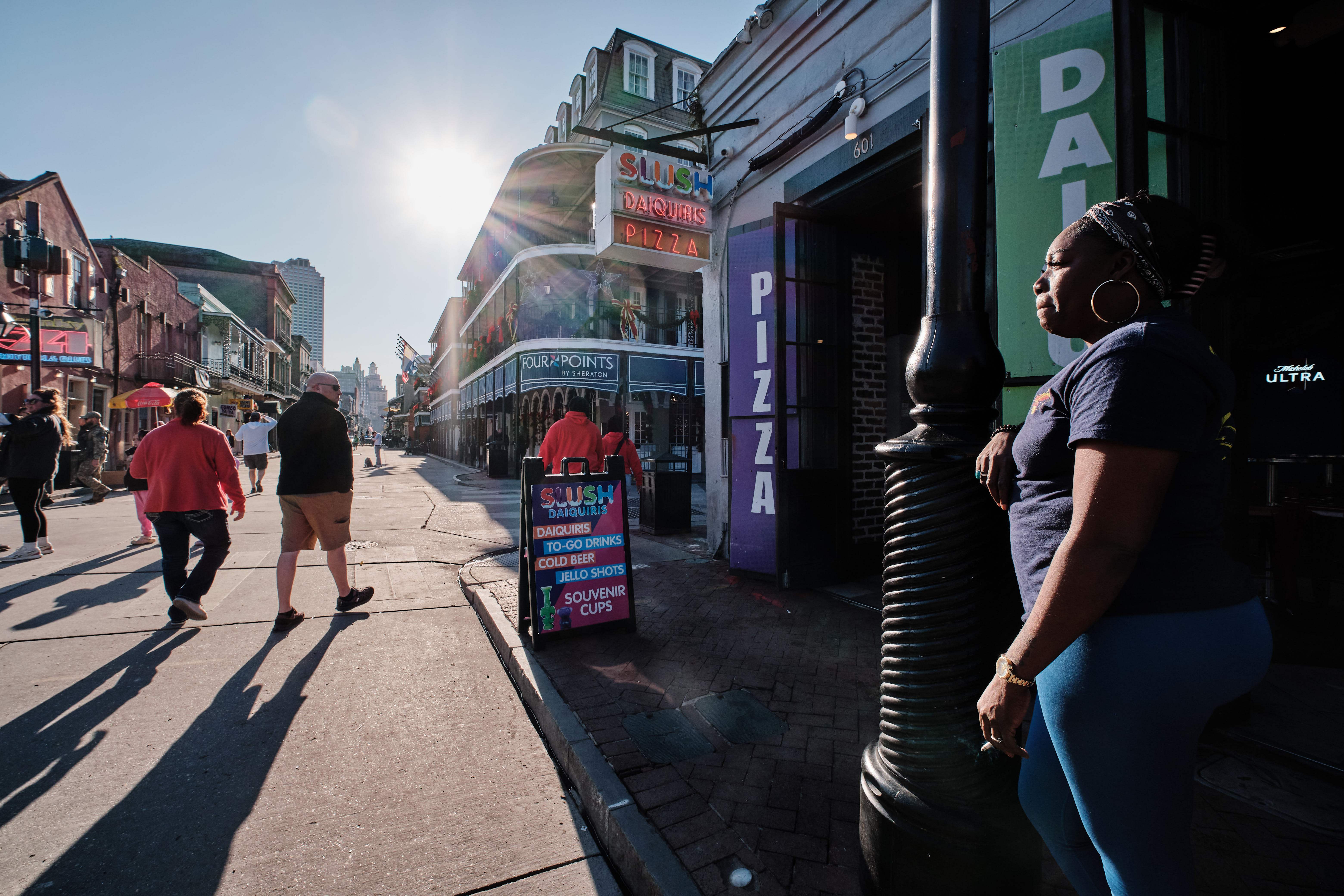 Slush Daiquiris employee Casandra Forman (R) smokes a cigarette outside her bar as she watches people walk on Bourbon Street after it is reopened to the public in New Orleans, Louisiana, USA, 02 January
