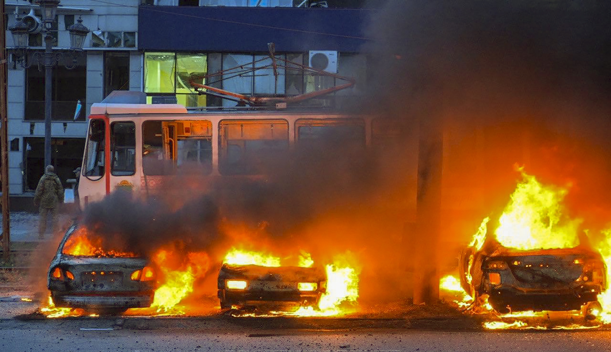Burning cars in front of a tram.