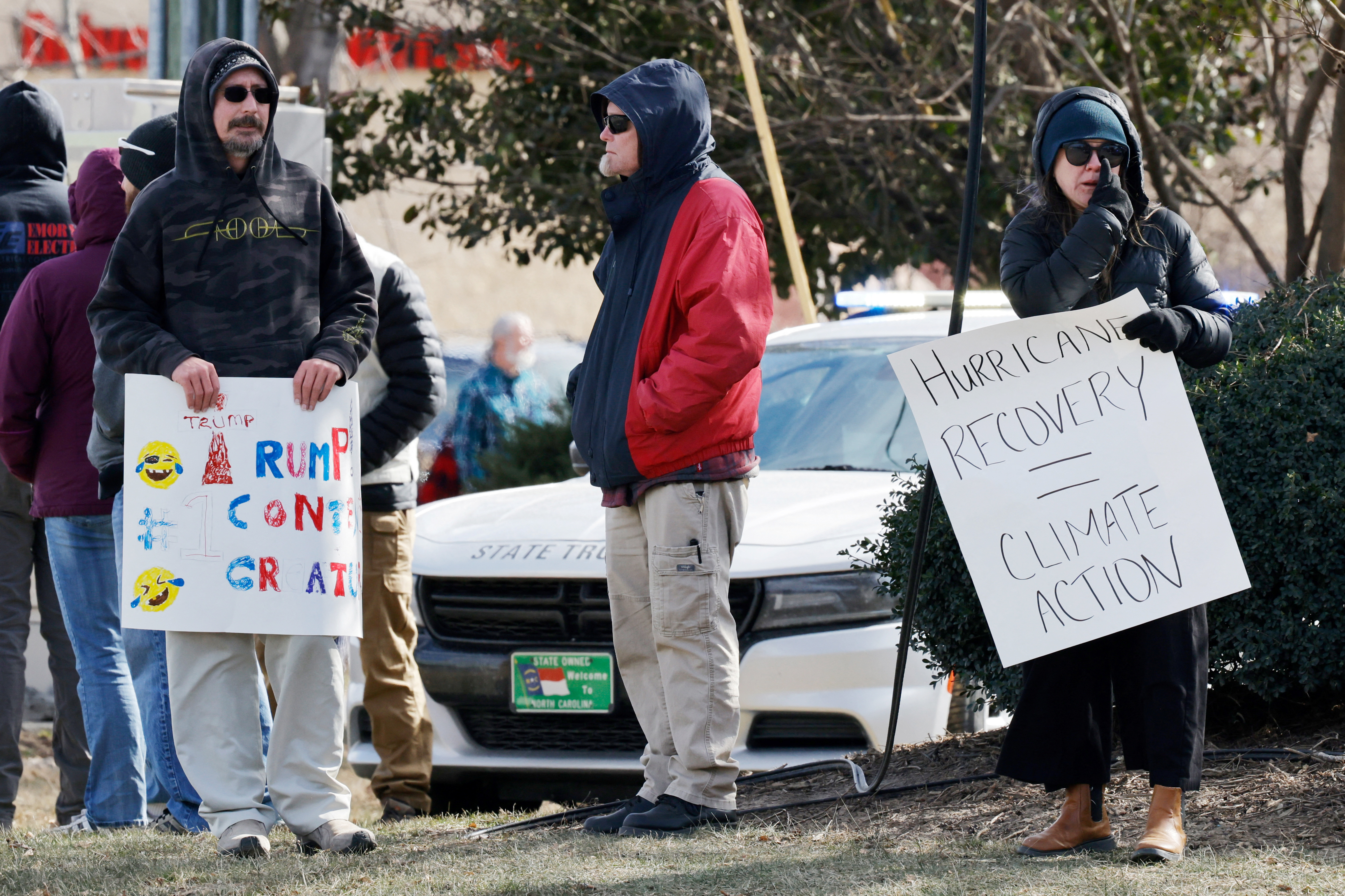 Protesters gather on the roadside for Trump's arrival in North Carolina with signs protesting his climate-change response