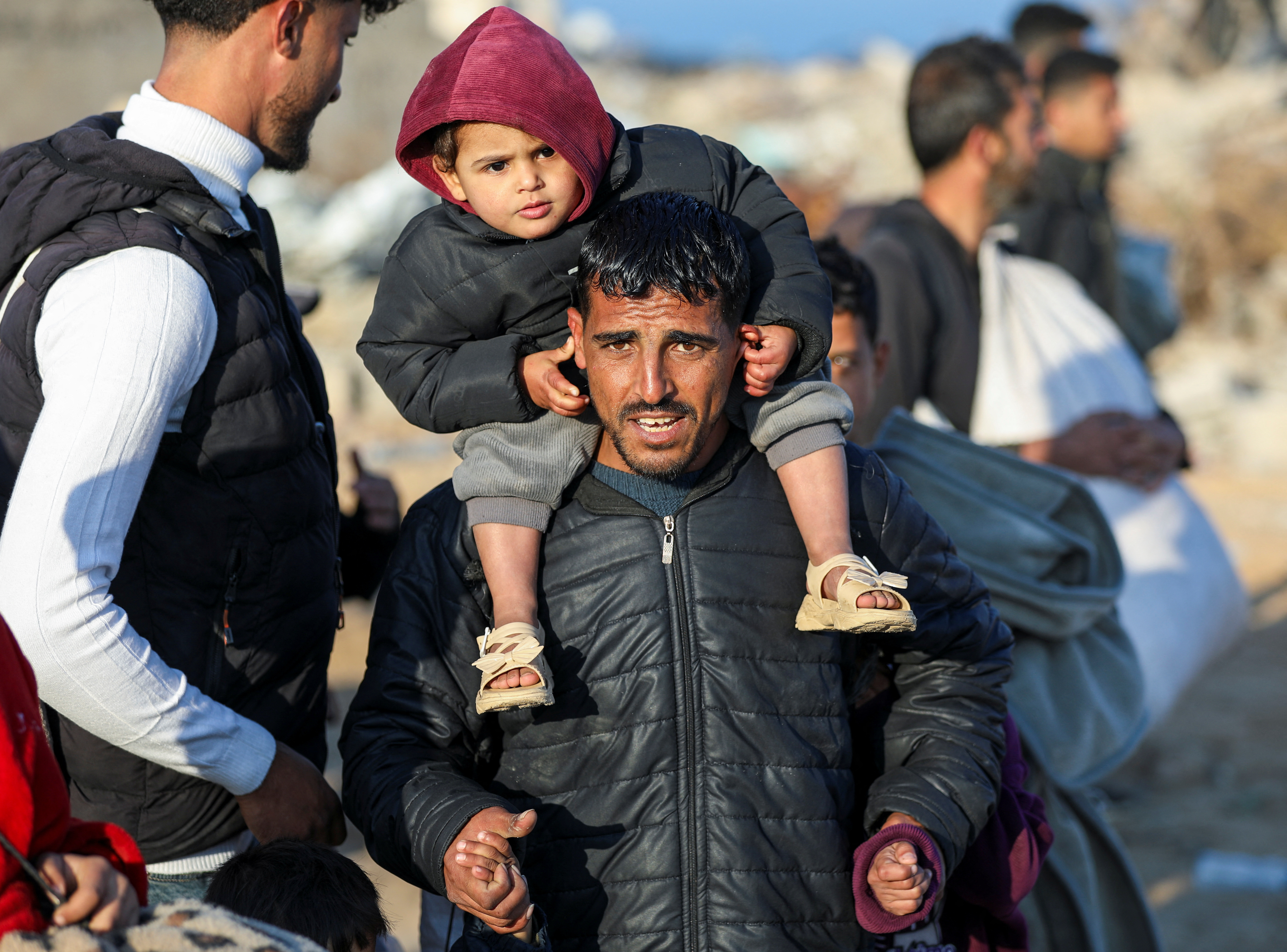 A Palestinian man, who was displaced to the south at Israel's order during the war, carries a child on his shoulders as he arrives on foot while making his way back to his home in the northern Gaza,