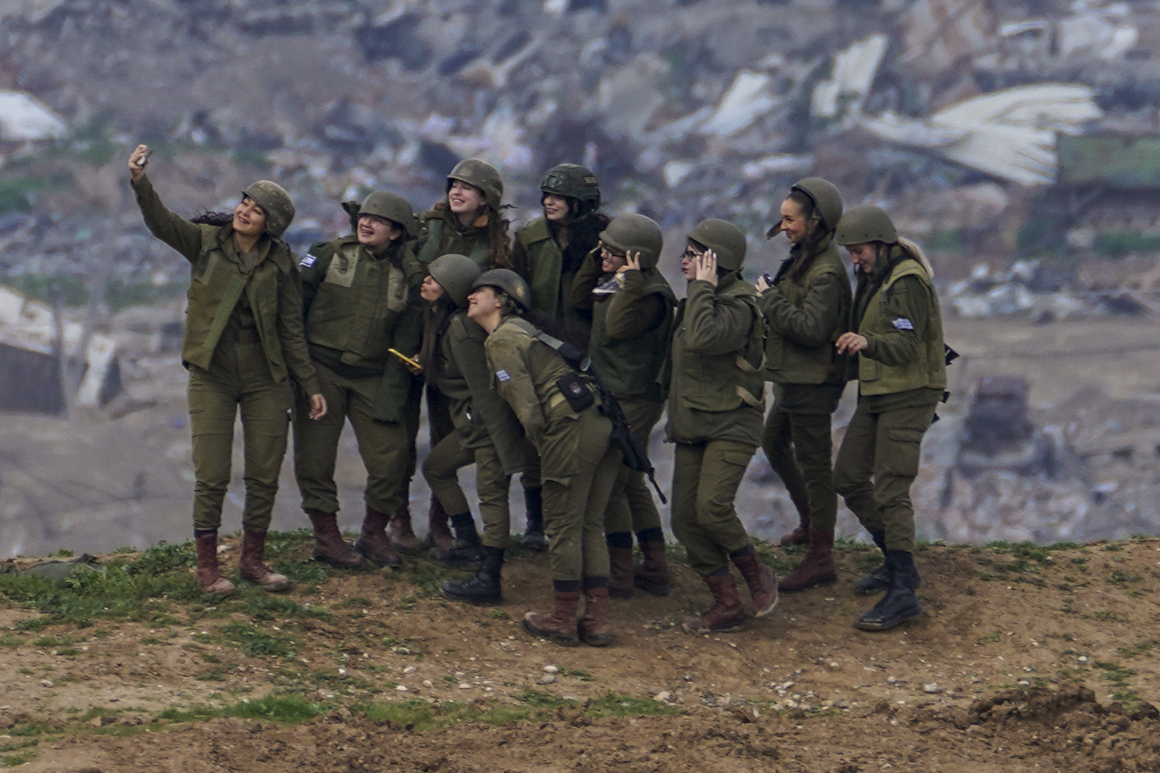 Israeli female soldiers pose for a photo on a position on the Gaza Strip border, in southern Israel, Monday, Feb. 19, 2024. (AP Photo/Tsafrir Abayov)
