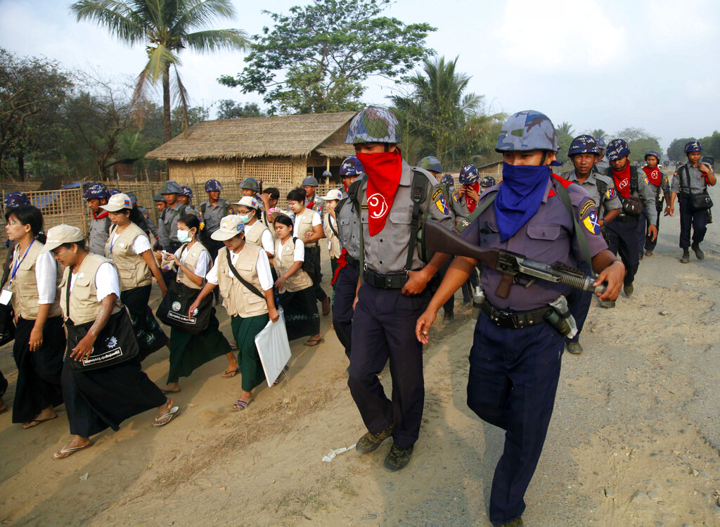 Policemen covers their faces to protect from the dust as they walk with census enumerators at Thae Chaung village in Sittwe, Rakhine State, western Myanmar, Tuesday, April 1, 2014. Enumerators fanned out across Myanmar on Sunday for a census that has been widely criticized for stoking religious and ethnic tensions, after the government denied members of a long-persecuted Muslim minority the right to identify themselves as "Rohingya." (AP Photo/Khin Maung Win)