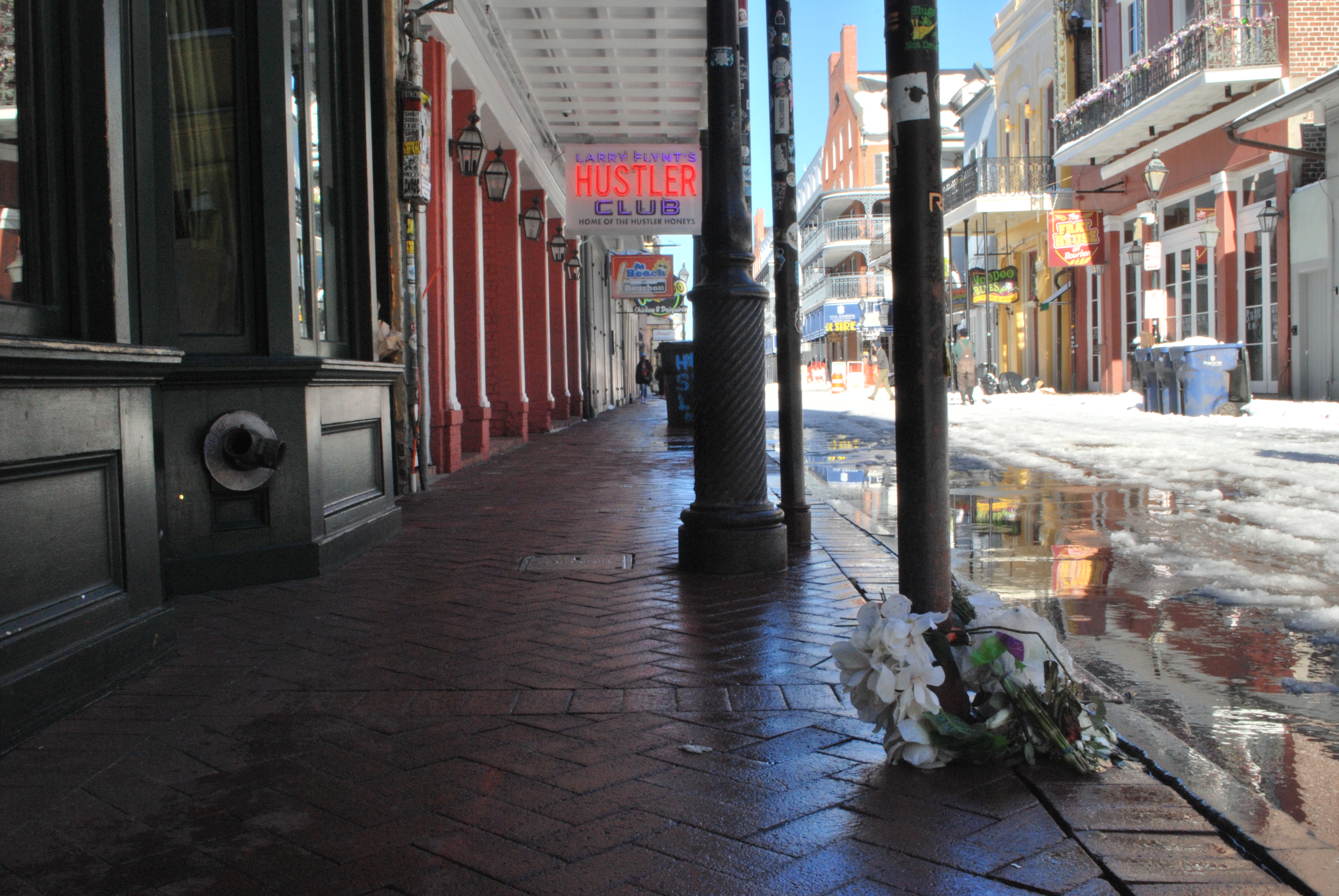 A wreath with white flowers sits wrapped around a pillar on Bourbon Street.