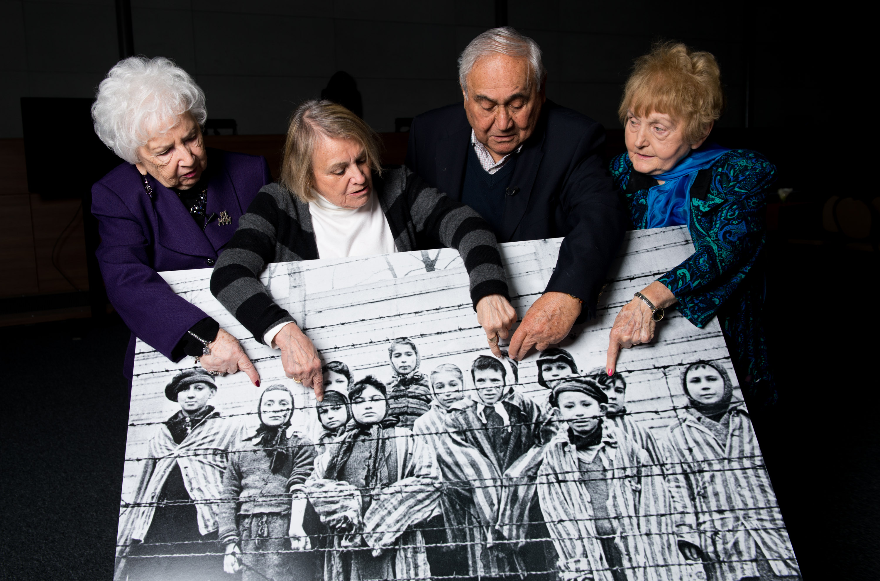 Survivors (left to right) Miriam Ziegler, 79, Paula Lebovics, 81, Gabor Hirsch, 85, and Eva Kor, 80, pose with an image of themselves as children taken at Auschwitz at the time of its liberation, on January 26, 2015 in Krakow, Poland