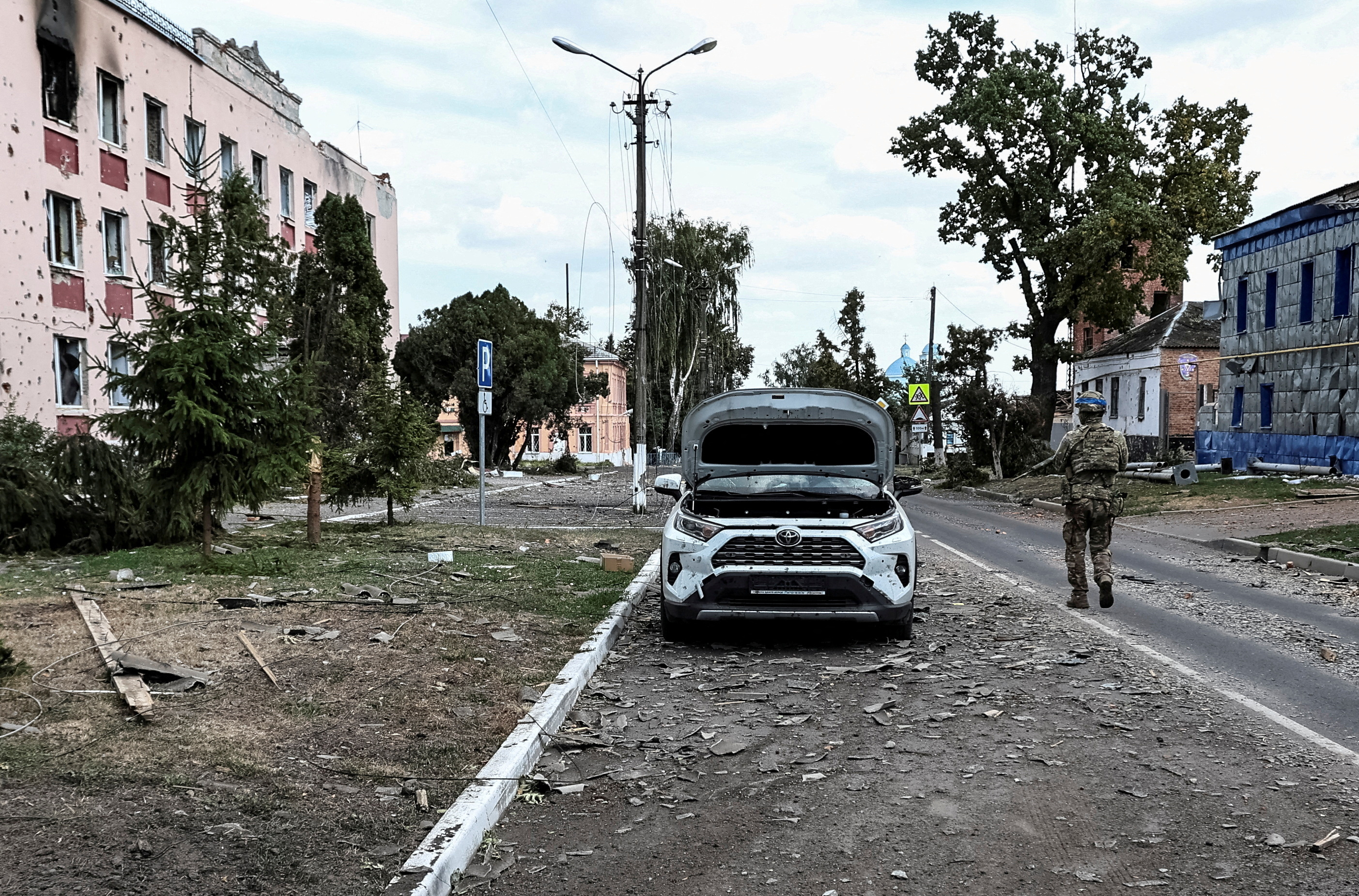 A Ukrainian serviceman patrols a street next to buildings damaged during recent fighting between Ukrainian and Russian forces
