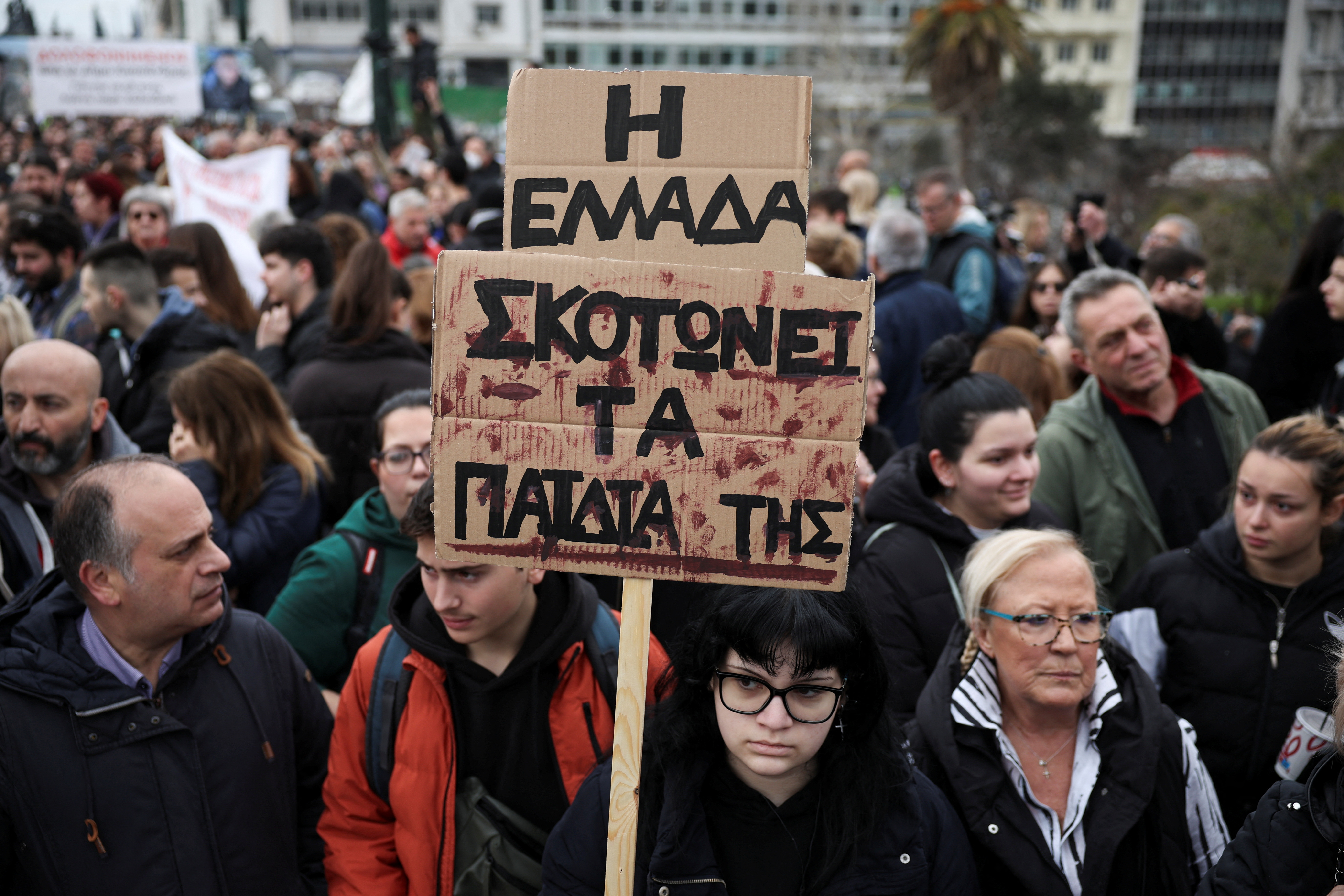 A person holds a placard saying 'Greece kills its children' as people gather in front of the Greek parliament during a protest, marking the second anniversary of the country's worst railway disaster, while an investigation continues, in Athens, Greece, February 28, 2025. REUTERS/Louisa Gouliamaki
