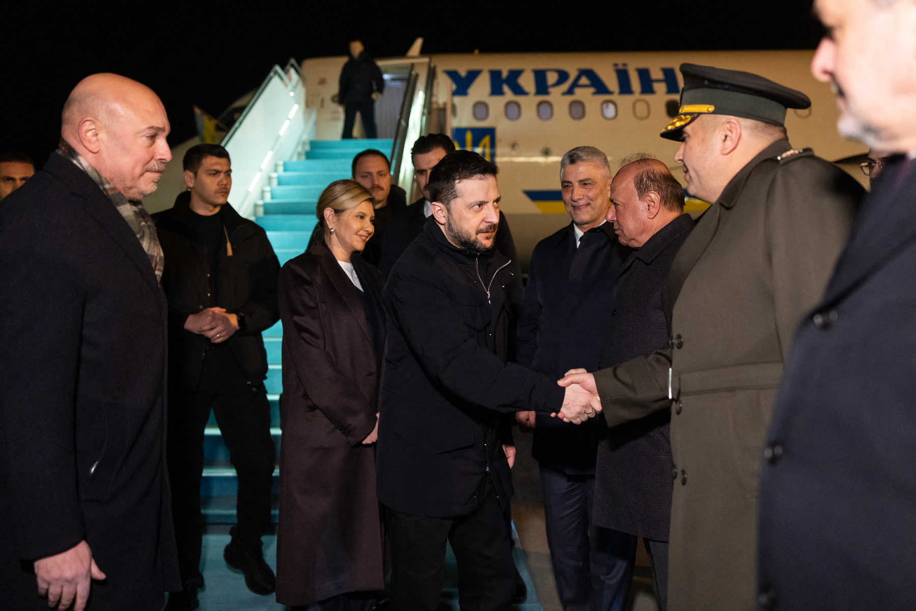 This handout photograph taken from Ukraine's President Volodymyr Zelensky's social media "X" account shows Ukrainian President Volodymyr Zelensky (C) shaking hands next to his wife Olena Zelenska (centre L) after their plane landed in Turkey on February 17, 2025. (Photo by Handout / X account of Volodymyr Zelensky / AFP) / RESTRICTED TO EDITORIAL USE - MANDATORY CREDIT "AFP PHOTO / X ACCOUNT OF VOLODYMYR ZELENSKY / HANDOUT" - NO MARKETING NO ADVERTISING CAMPAIGNS - DISTRIBUTED AS A SERVICE TO CLIENTS