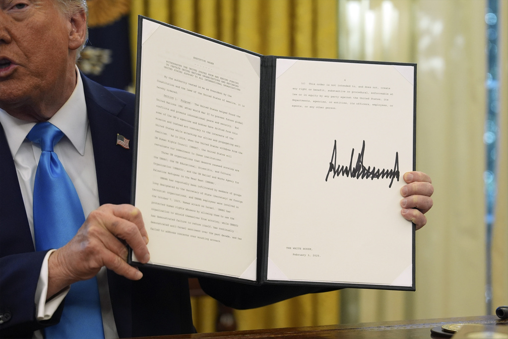 a man holds paper with a large black signature on it