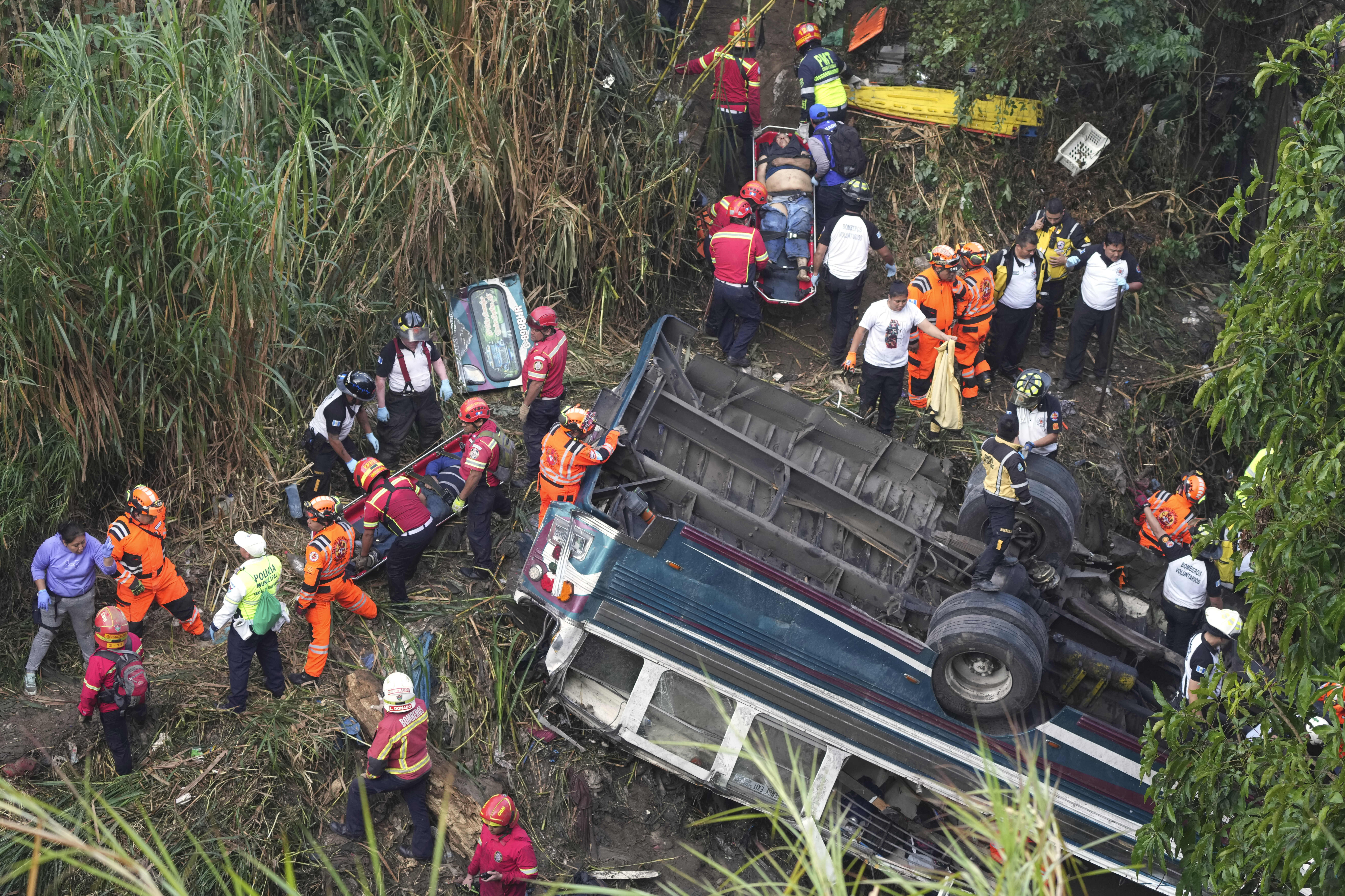 Firefighters work at the scene of a bus that fell from a bridge on the outskirts of Guatemala City