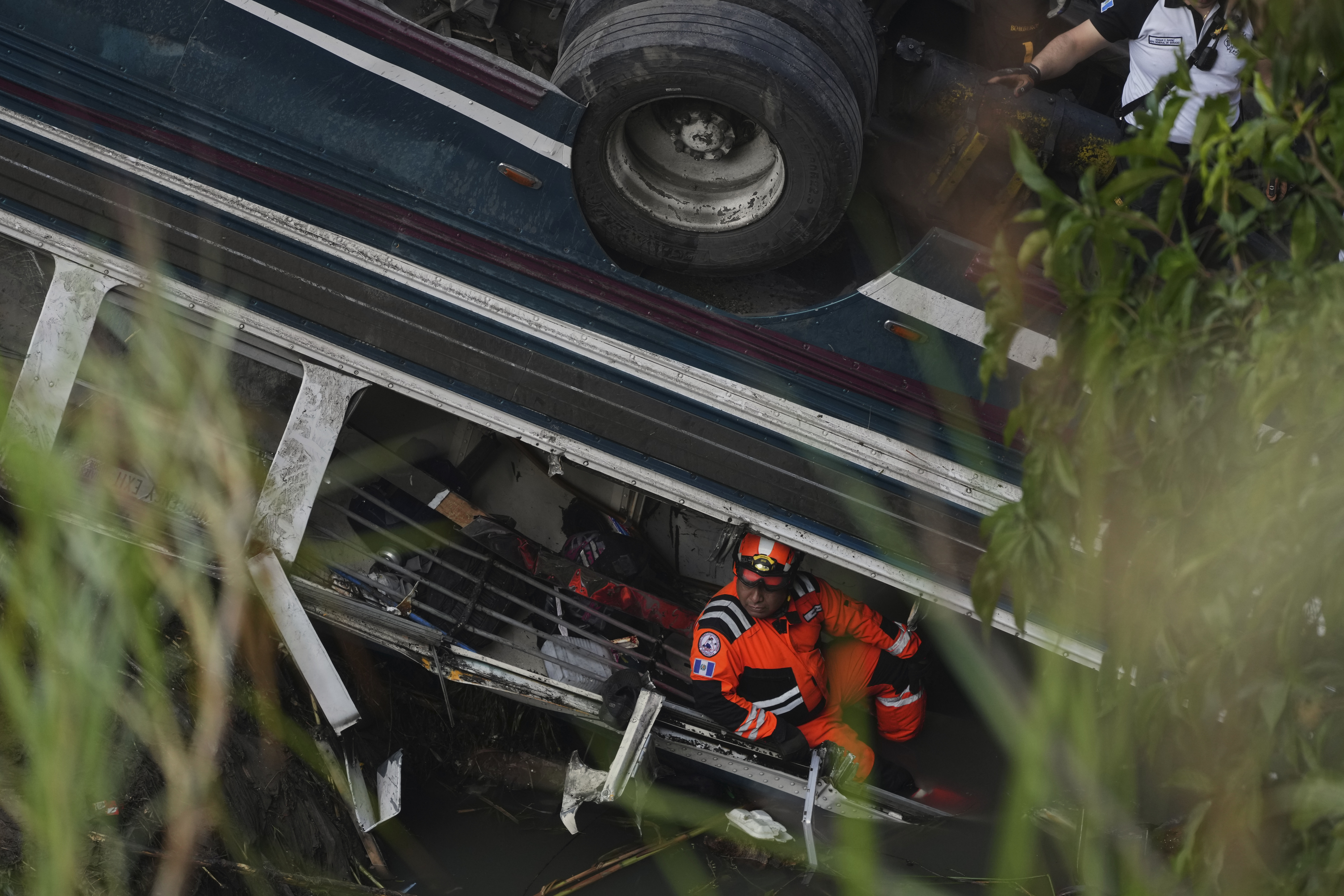 A firefighter works inside a bus that fell from a bridge on the outskirts of Guatemala City