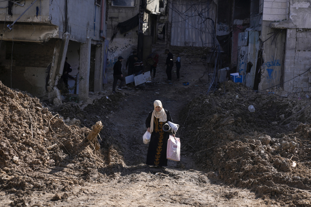a woman walks through a destroyed street with her belongings
