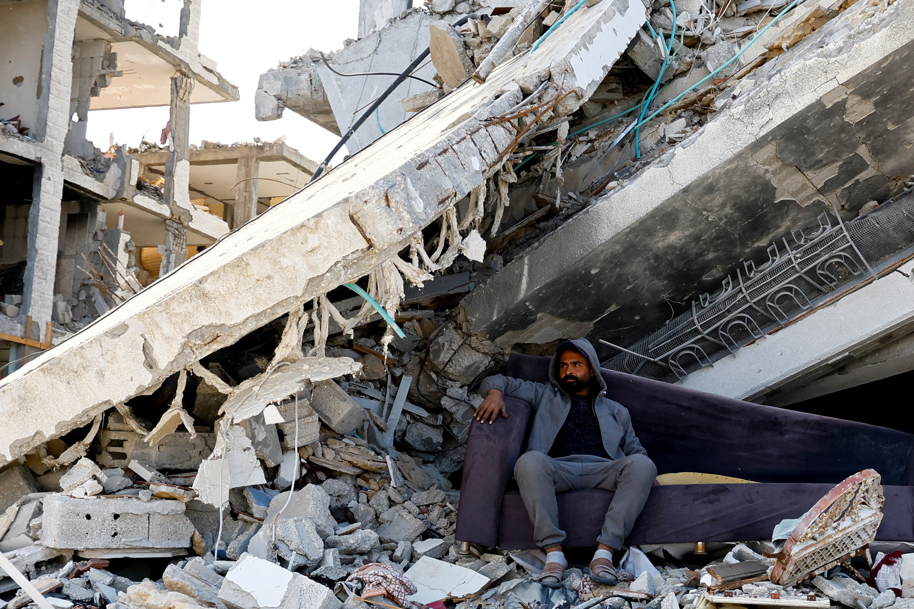 A Palestinian man sits amidst the rubble of buildings destroyed during the Israeli offensive, amid a ceasefire between Israel and Hamas, in Rafah.