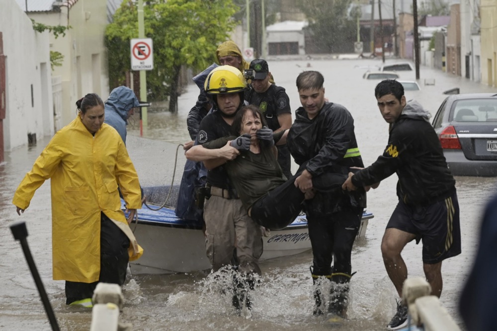 Emergency personnel assist a woman affected during a flood due to heavy rains.