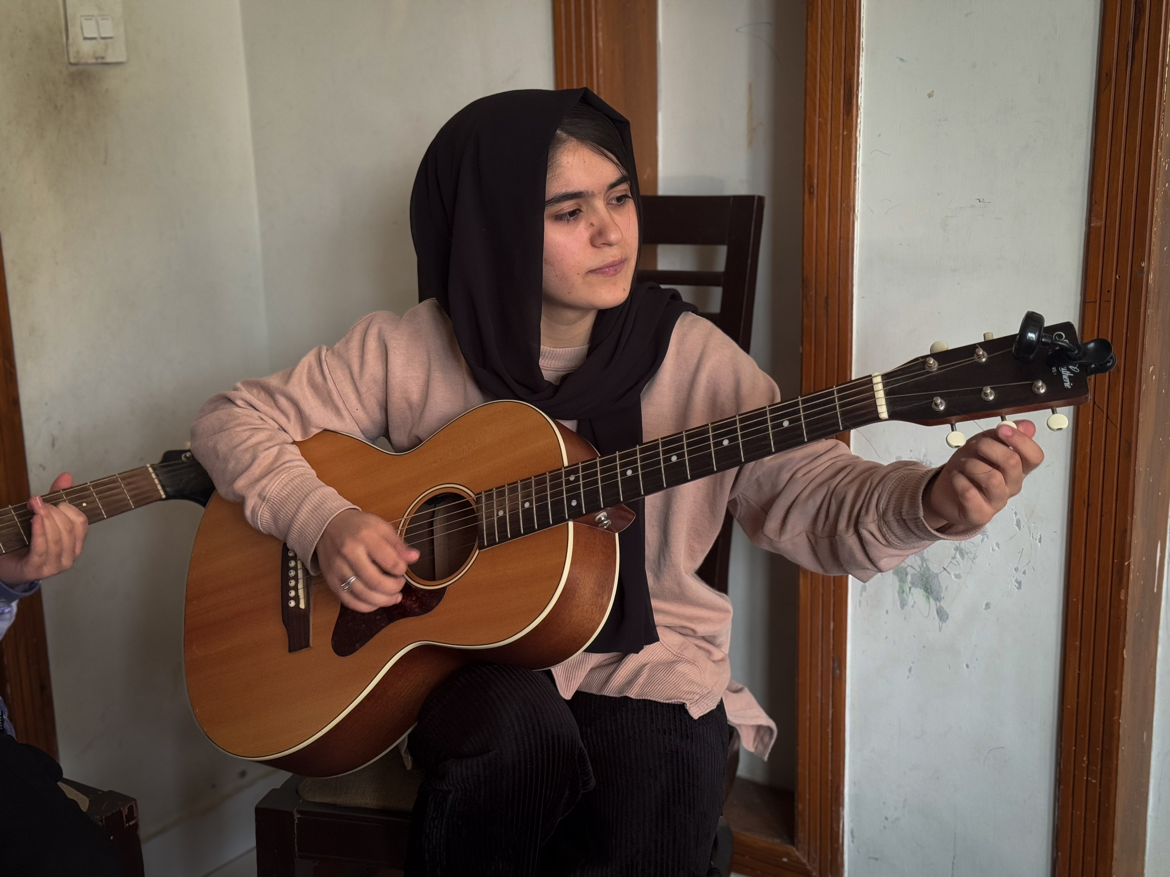 Yasemin – aka Jellybean – sets the strings of her guitar before playing a tune at her home in Islamabad, Pakistan on February 14, 2025
