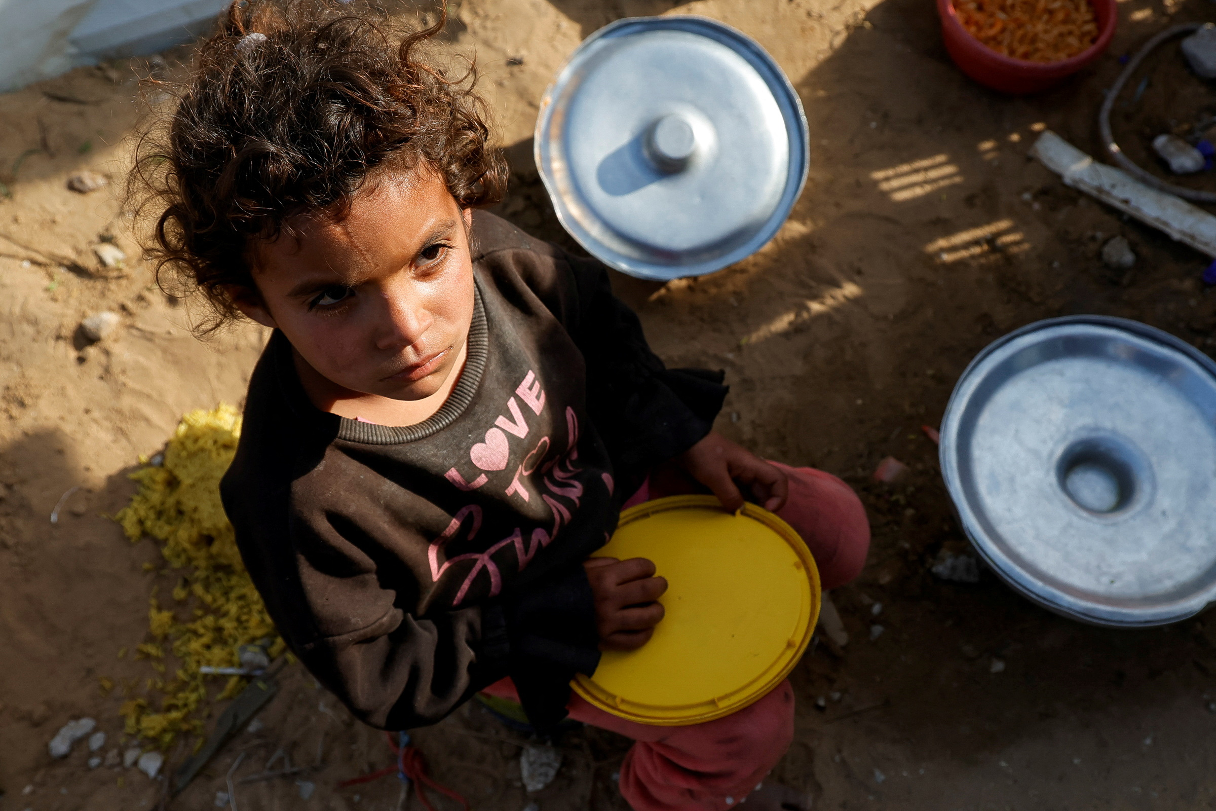 A Palestinian child waits to receive food cooked by a charity kitchen, in Rafah, in the southern Gaza Strip, March 13, 2025. [Hatem Khaled/Reuters]