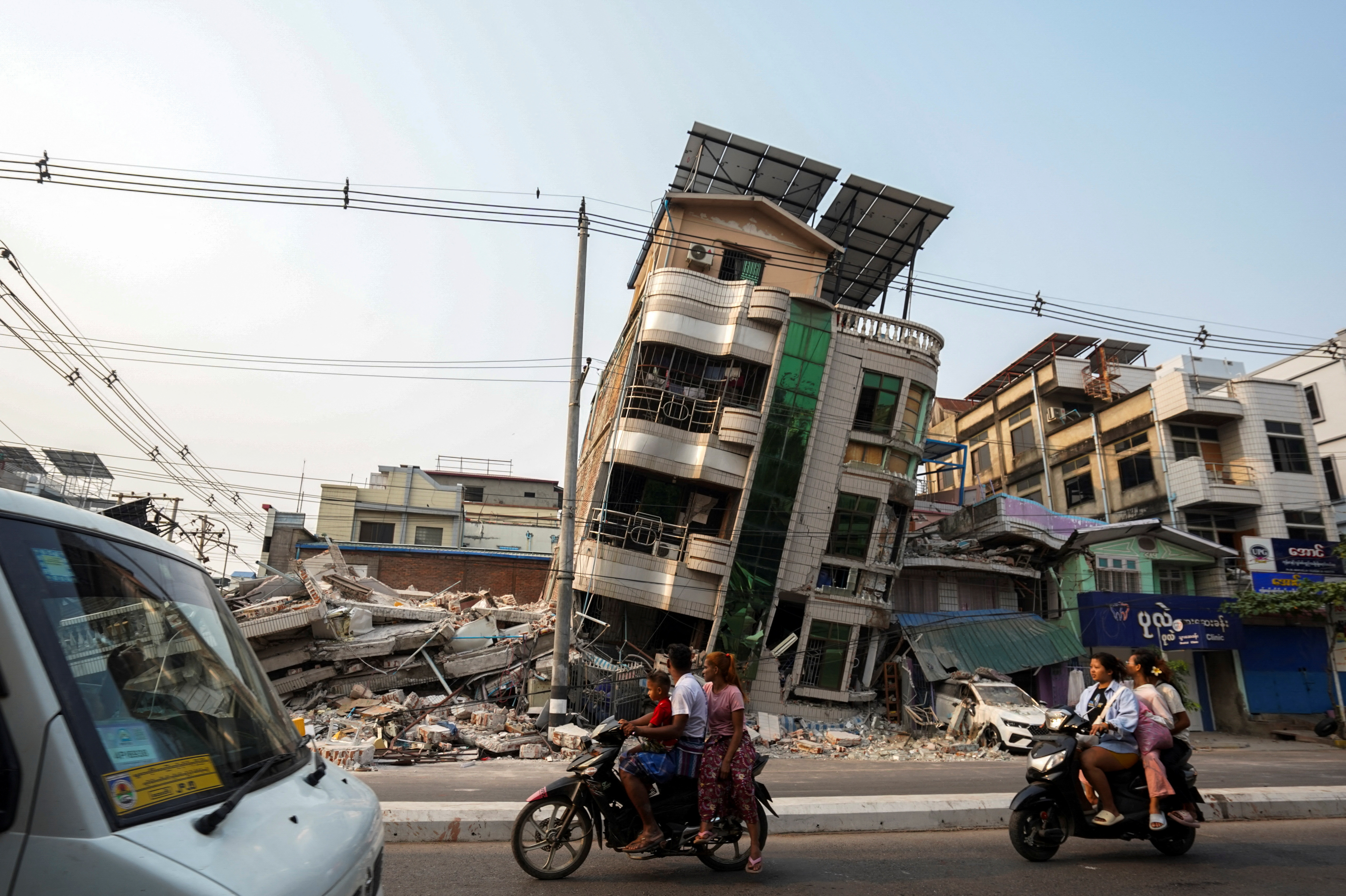 Commuters drive past a building that collapsed