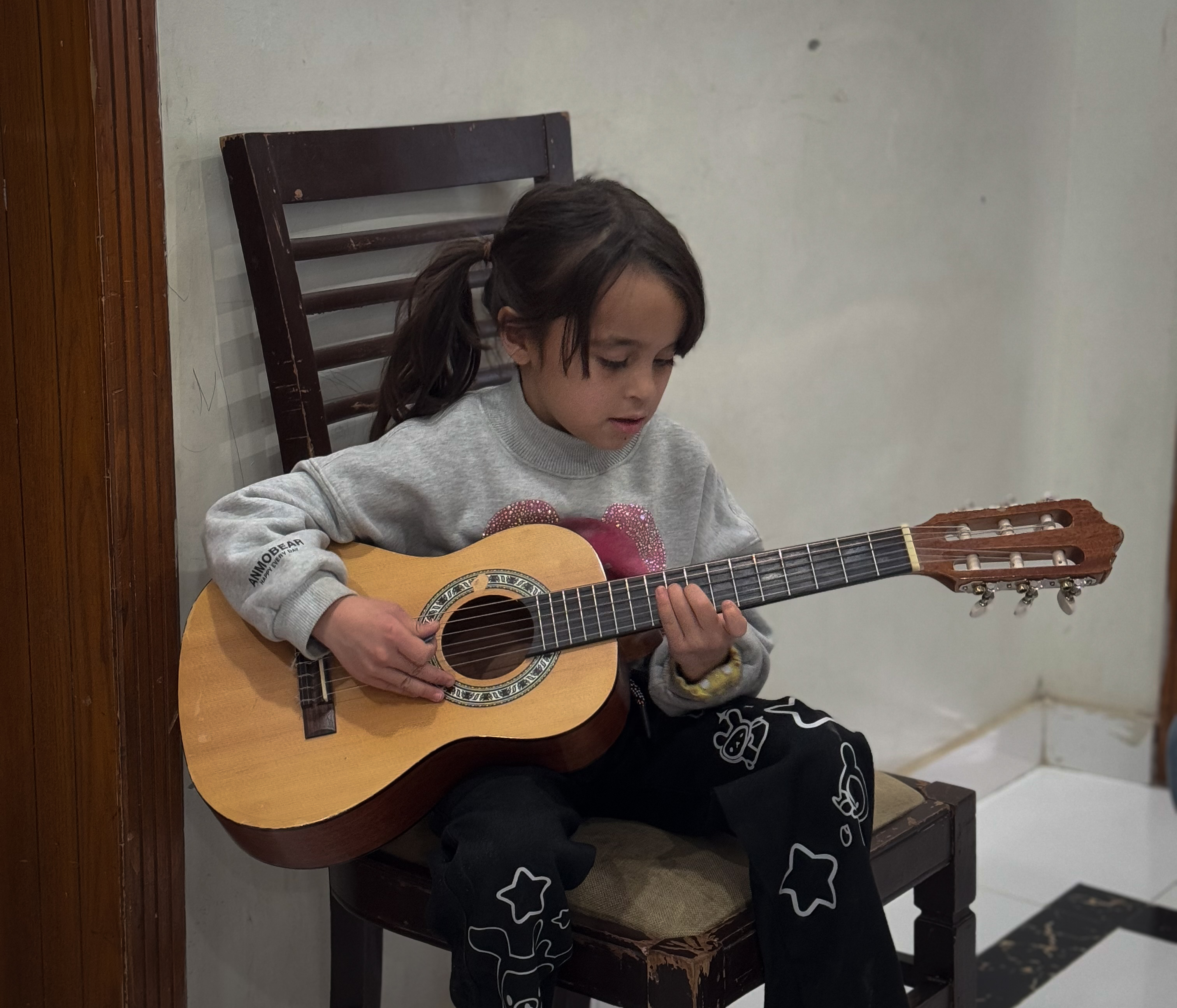Little Uzra holds her small guitar as she practises a tune at her home in Islamabad, Pakistan
