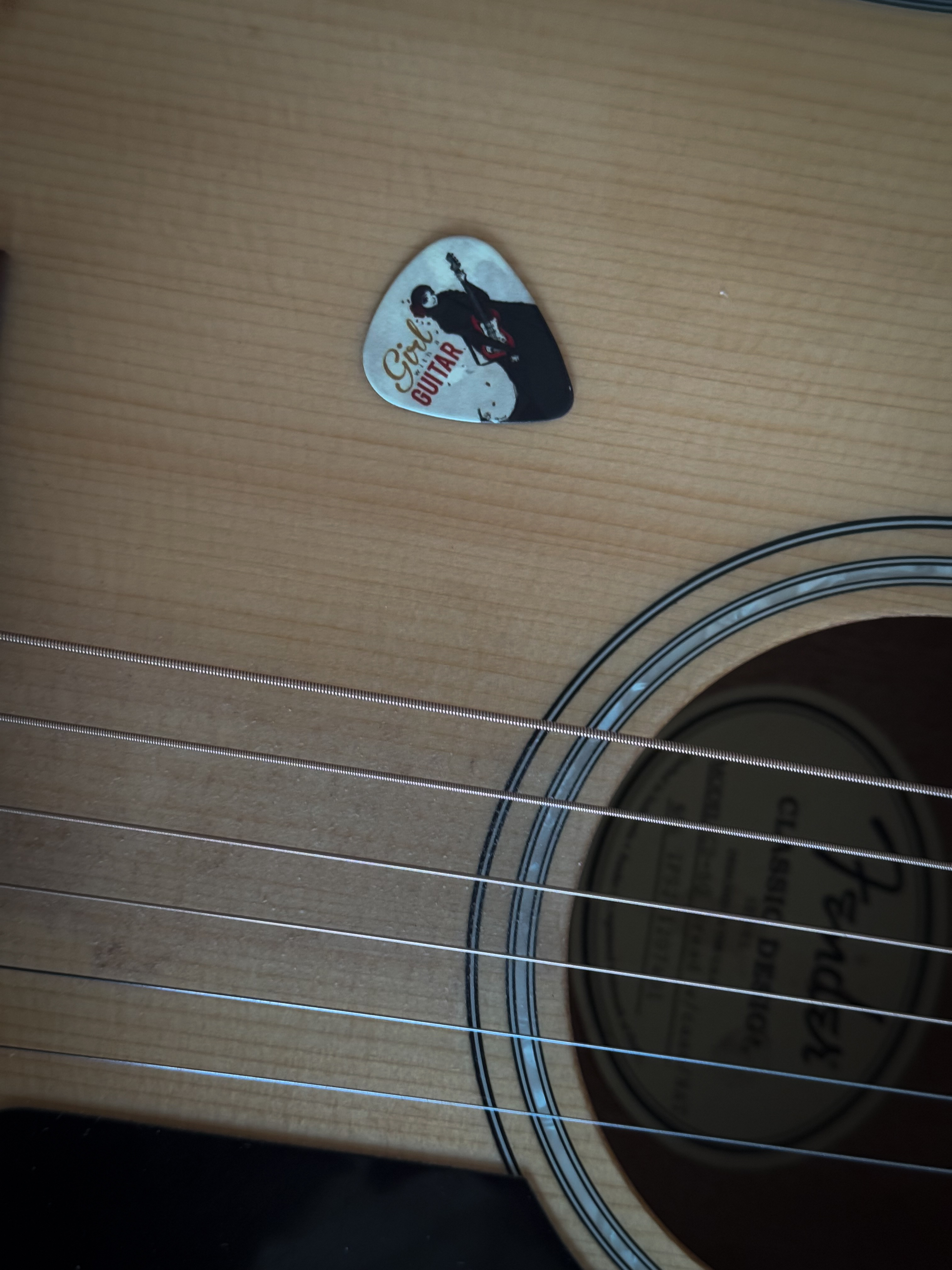 A custom guitar pick featuring the band’s original track, ‘Girl with a Guitar’