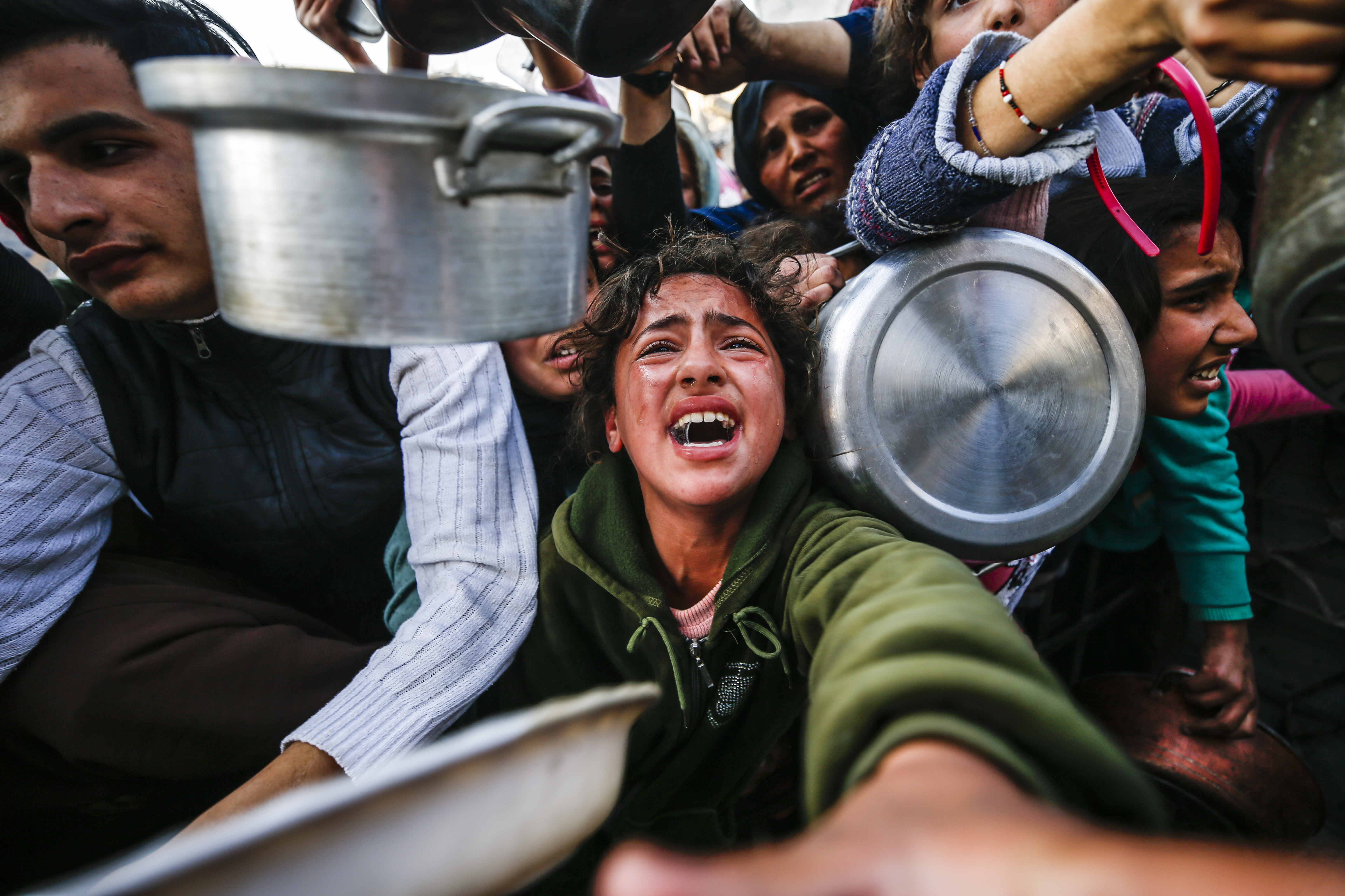 GAZA CITY, GAZA - MARCH 11: Palestinians wait in long queues to receive pots of food as they face food crisis following the end of the first phase of the ceasefire agreement, which lasted for 42 days, Israel stopped all humanitarian aid supplies from entering the Gaza Strip at the Jabalia Refugee Camp in Gaza Strip on March 11, 2025. The closure of the Kerem Abu Salim Border Crossing is exacerbating the fuel and food crisis. By violating the ceasefire agreement and blocking the entry of humanitarian aid, Israel is implementing a 'systematic and deliberate' policy of starvation against Palestinians in the Gaza Strip. Palestinians living in the Jabalia Camp area in northern Gaza are forced to wait in long queues to receive food distributed by charities. ( Mahmoud İssa - Anadolu Agency )