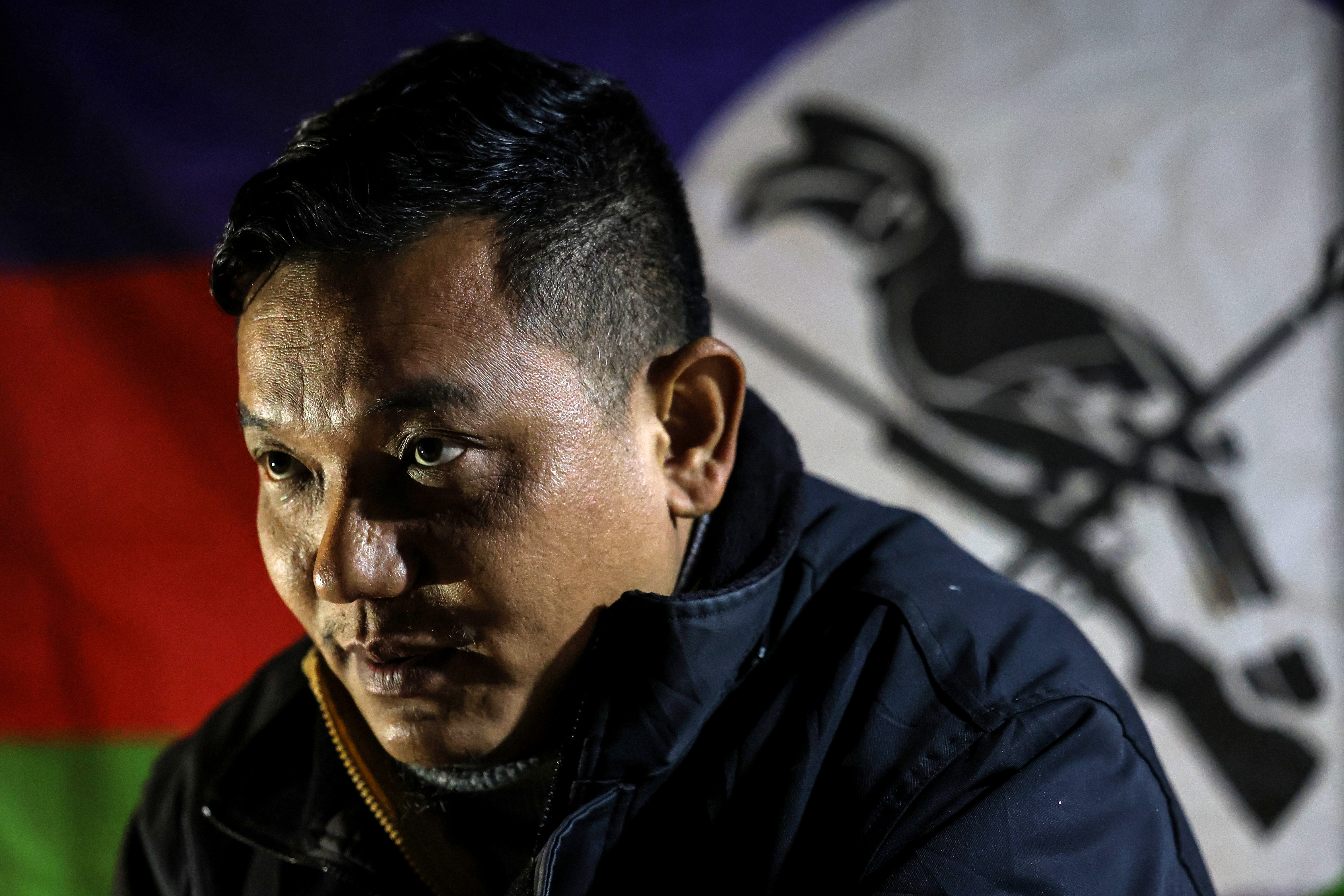 Peter Thang, Chin National Defence Force (CNDF) vice president, sits in front of the CNDF flag during an interview in a village at the frontline in Falam, Chin State, Myanmar, January 2, 2025. [Valeria Mongelli/Al Jazeera]