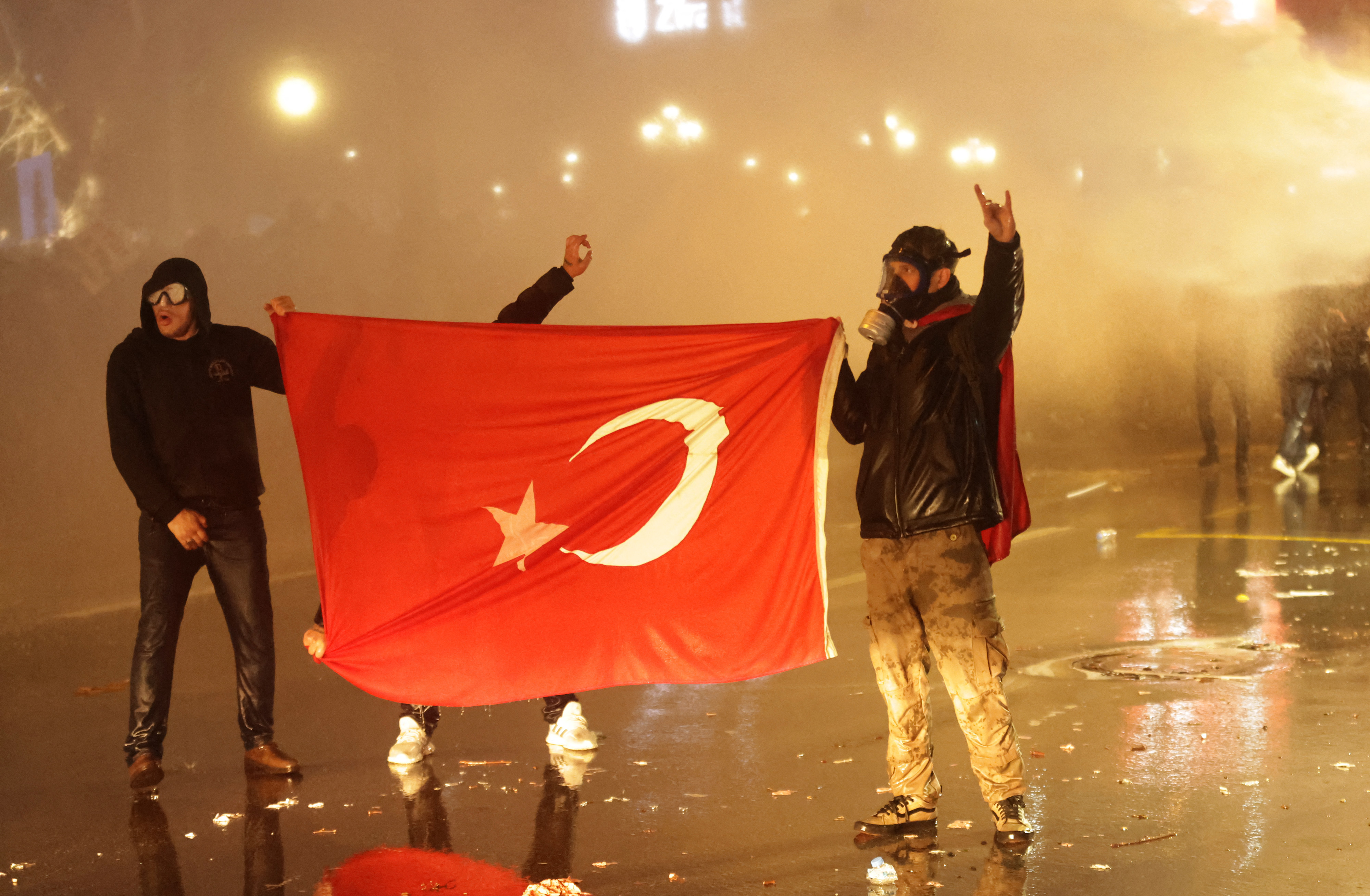 Protesters hold a Turkish national flag as they clash with Turkish antiriot police.