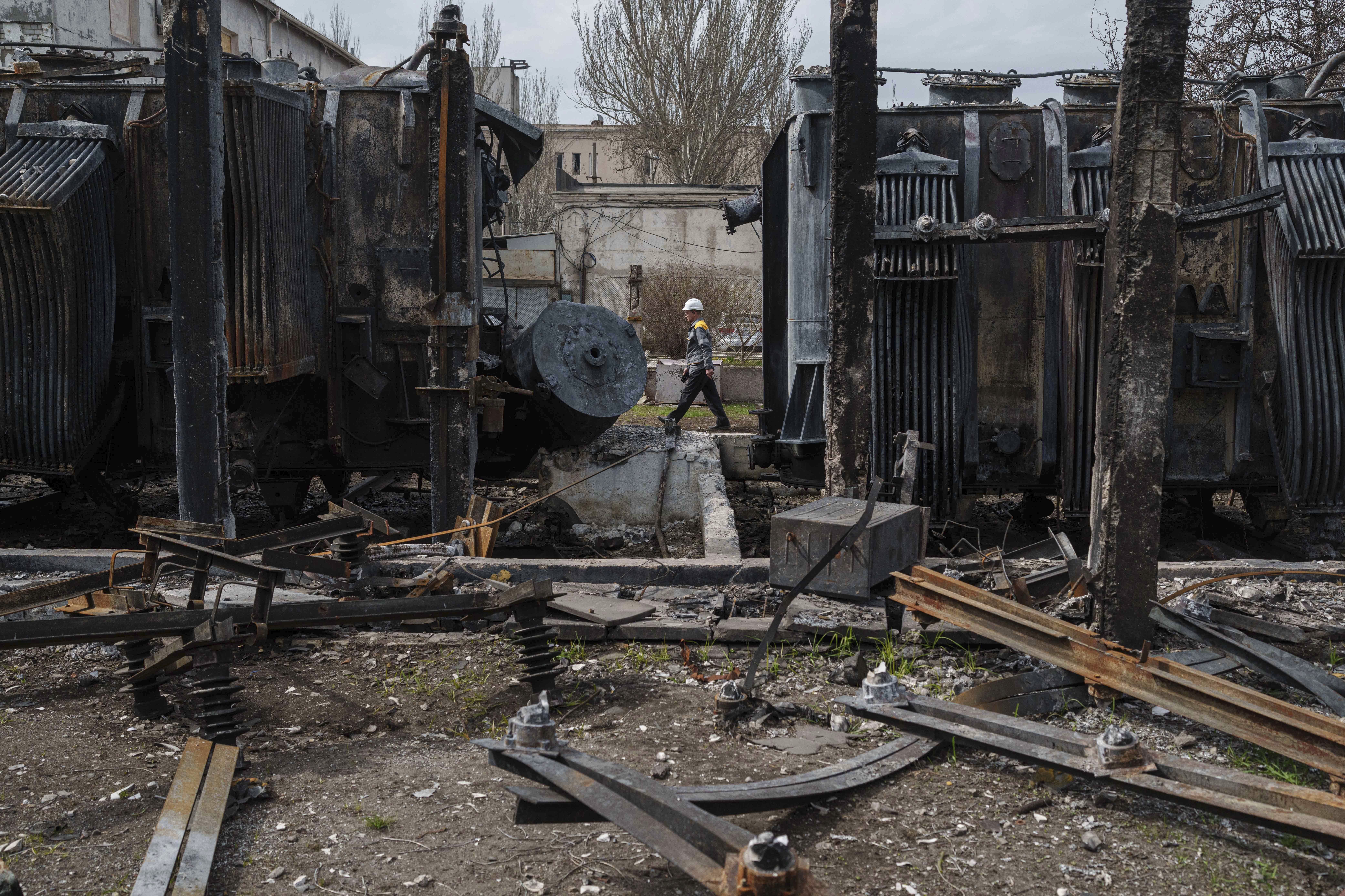 A worker of DTEK company walks in front of transformers of a substation destroyed by a Russian drone strike