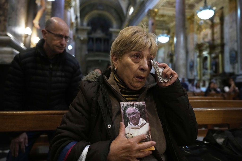 Woman holds photo of pope as she wipes tear off her eyes
