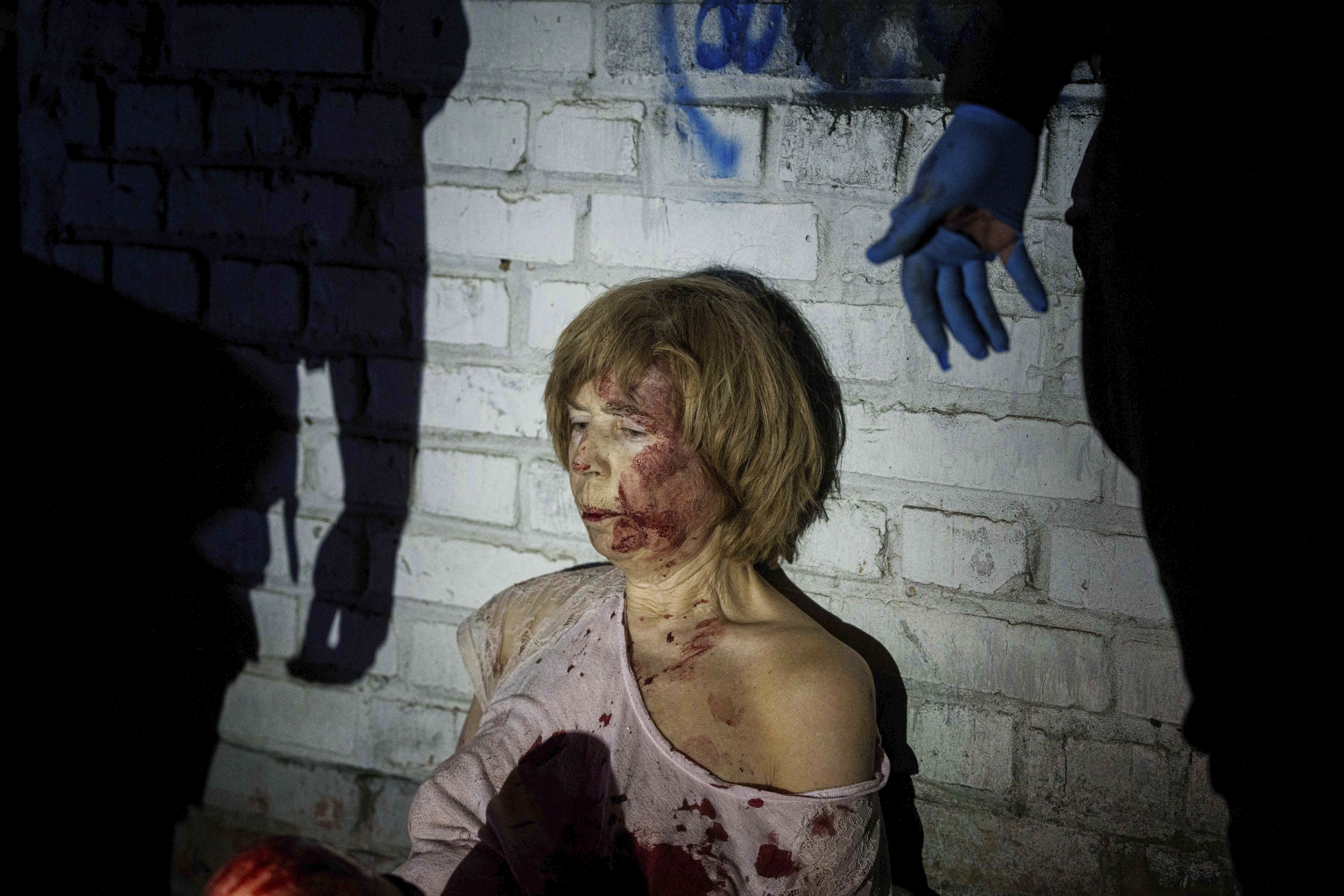 An injured woman sits near her house, which was damaged by a Russian airstrike