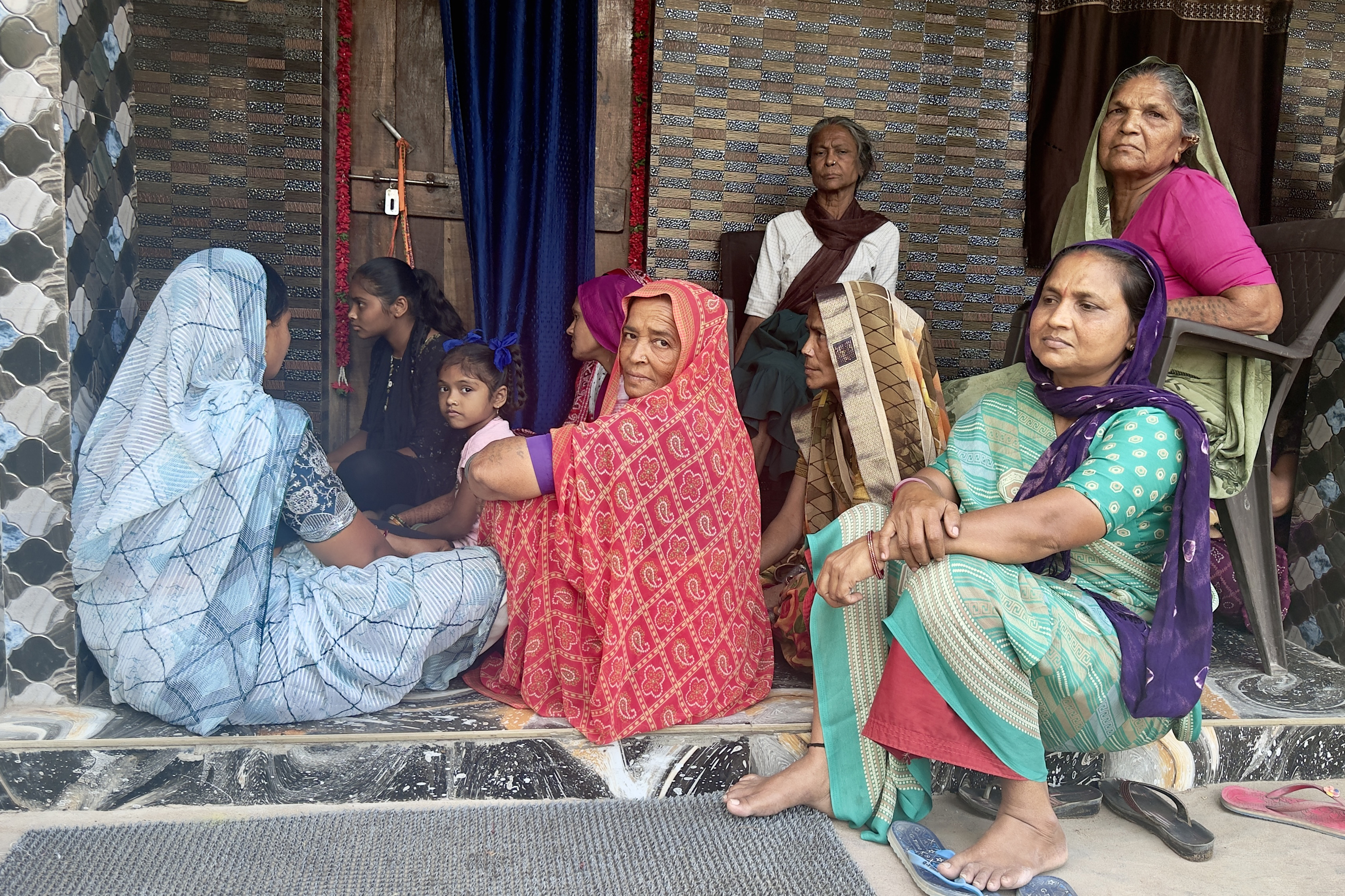 Family members of Indian fishermen jailed in Pakistan sit outside a house in Diu