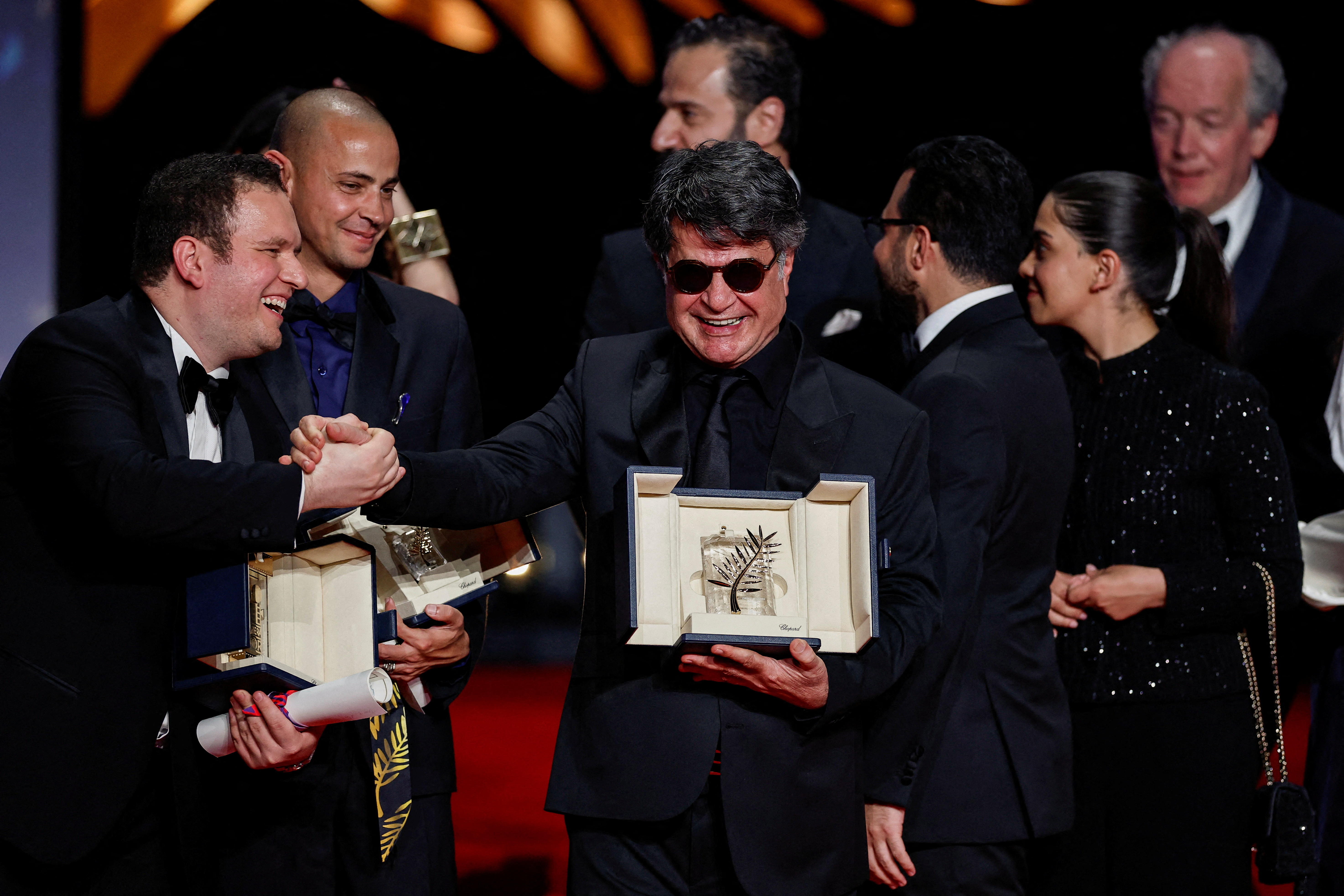 Director Jafar Panahi, Palme d'Or award winner for the film "Un simple accident" (It Was Just an Accident), shakes hands with director Hasan Hadi, Camera d'Or award winner for the film "The President's Cake" (Mamlaket al-Qasab) on stage during the closing ceremony of the 78th Cannes Film Festival in Cannes, France, May 24, 2025. REUTERS/Benoit Tessier TPX IMAGES OF THE DAY