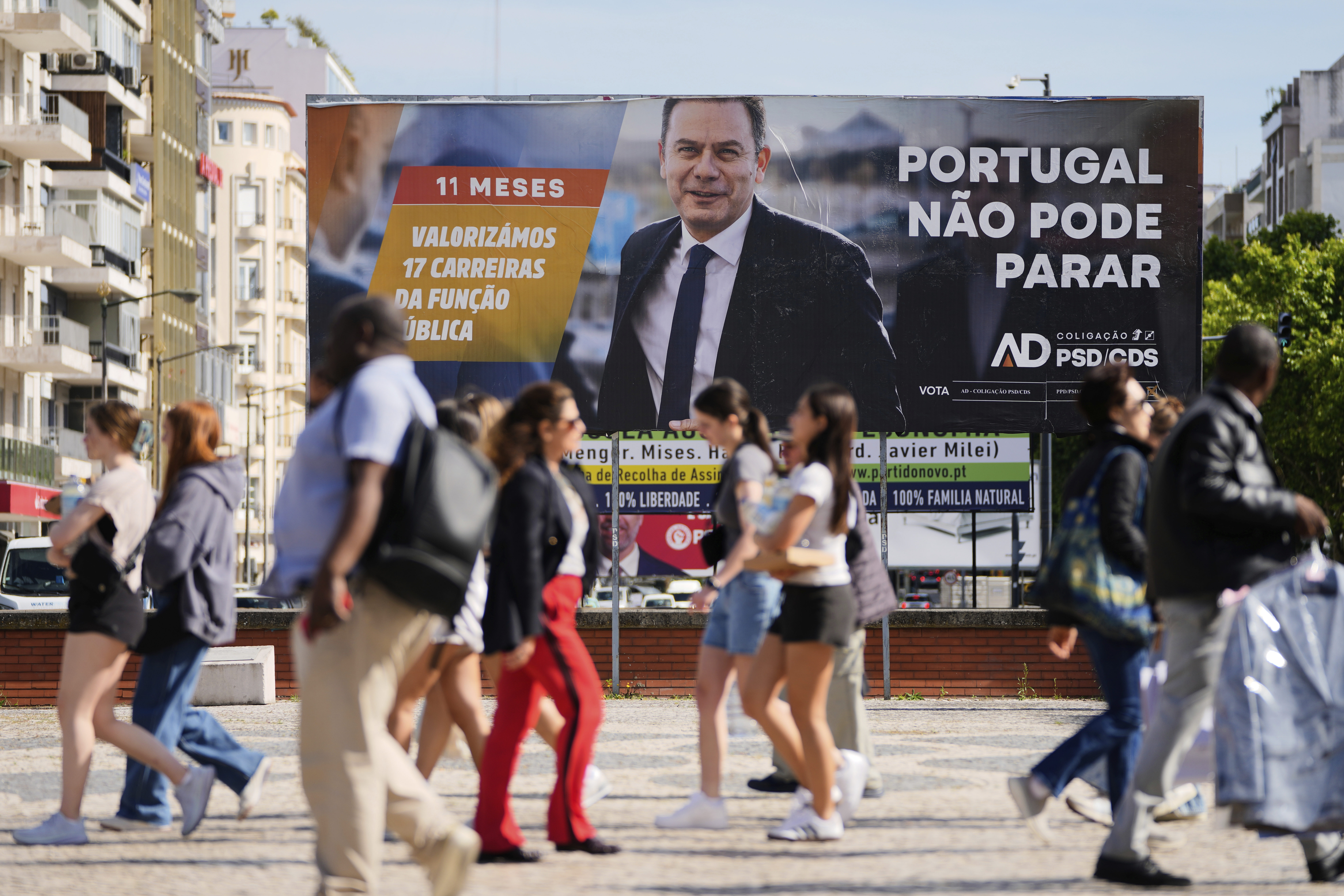 People walk past an election campaign billboard ahead oif Portugal's general election.