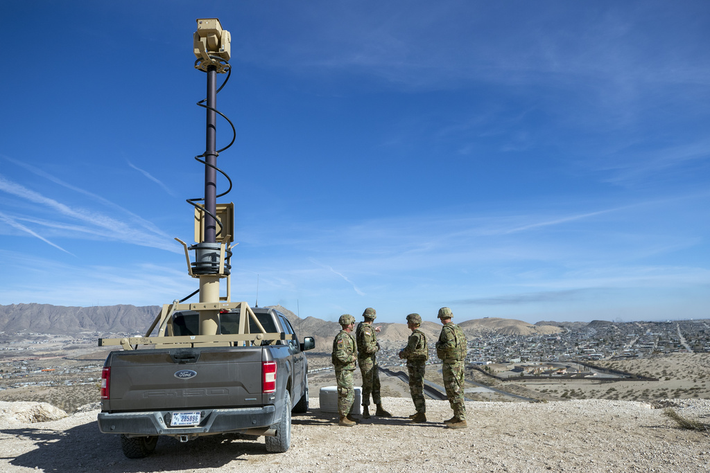 Soldiers stand around a surveillance vehicle
