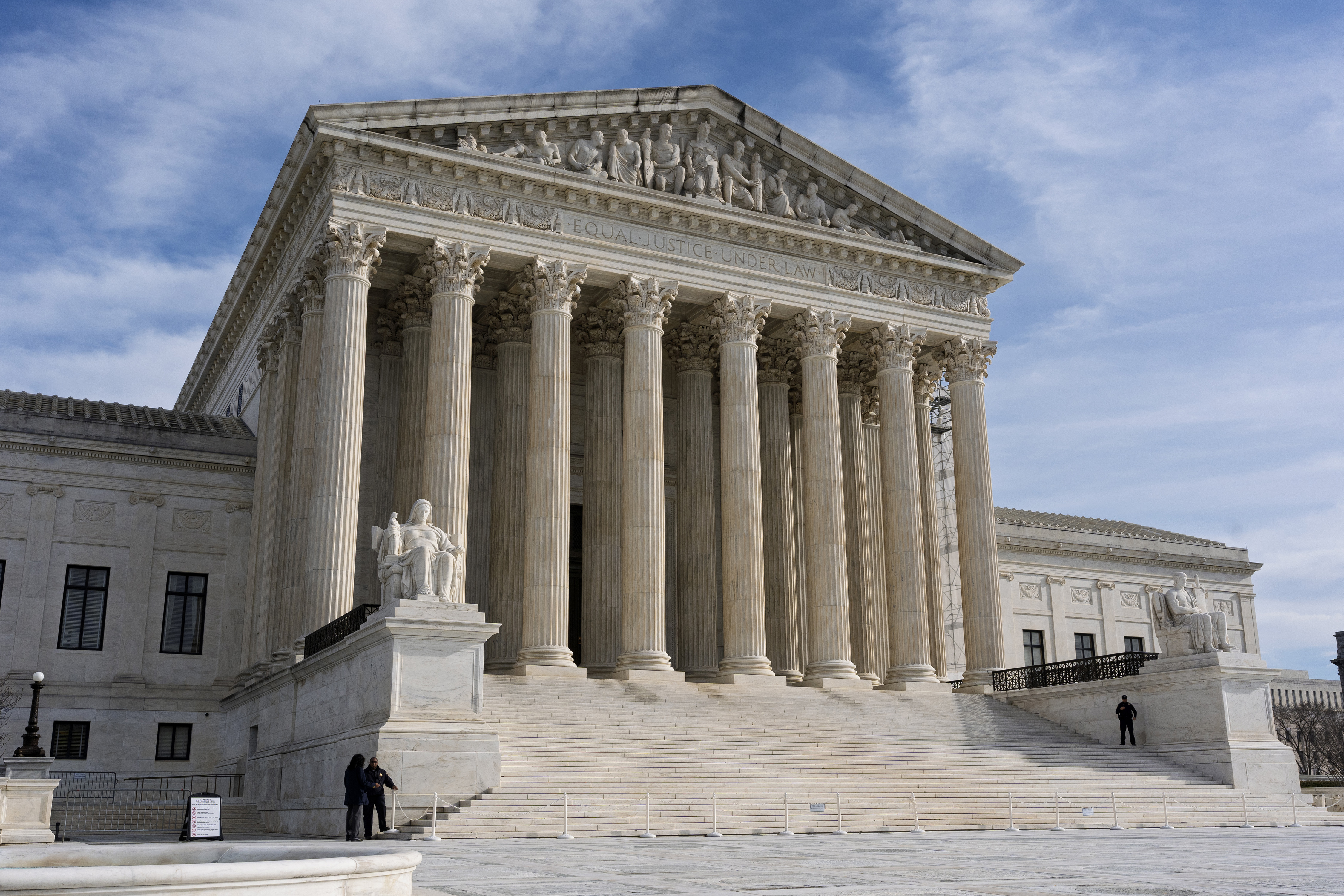 The US Supreme Court building, seen on a cloudy, blue-sky day.