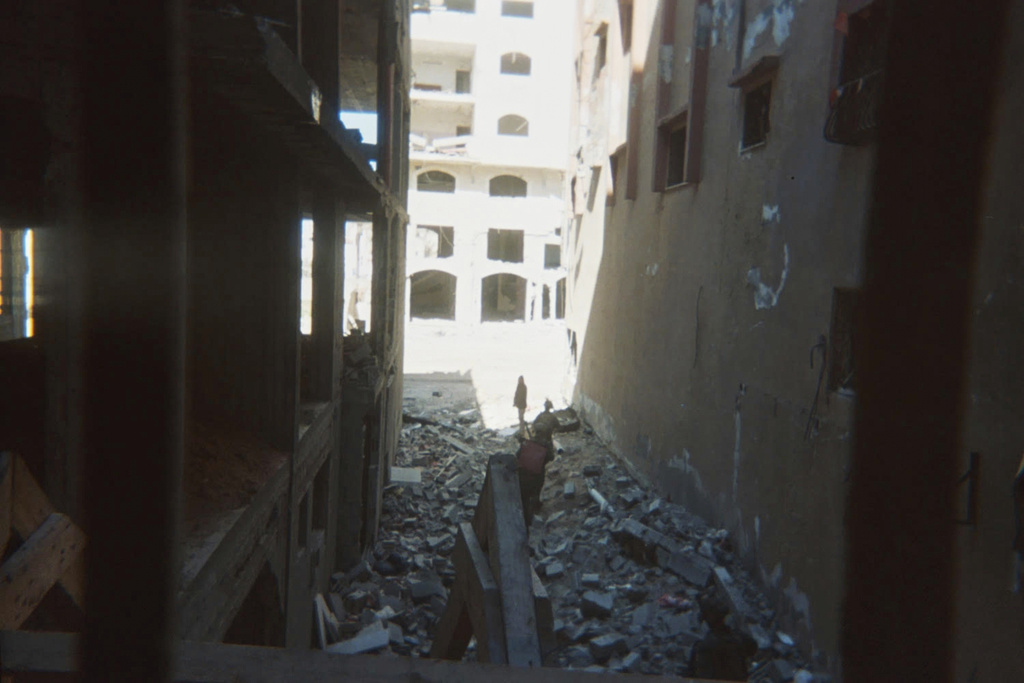 This photo provided by Breaking the Silence, a whistleblower group of former Israeli soldiers, shows two soldiers behind Palestinian detainees being sent into a Gaza City-area house to clear it