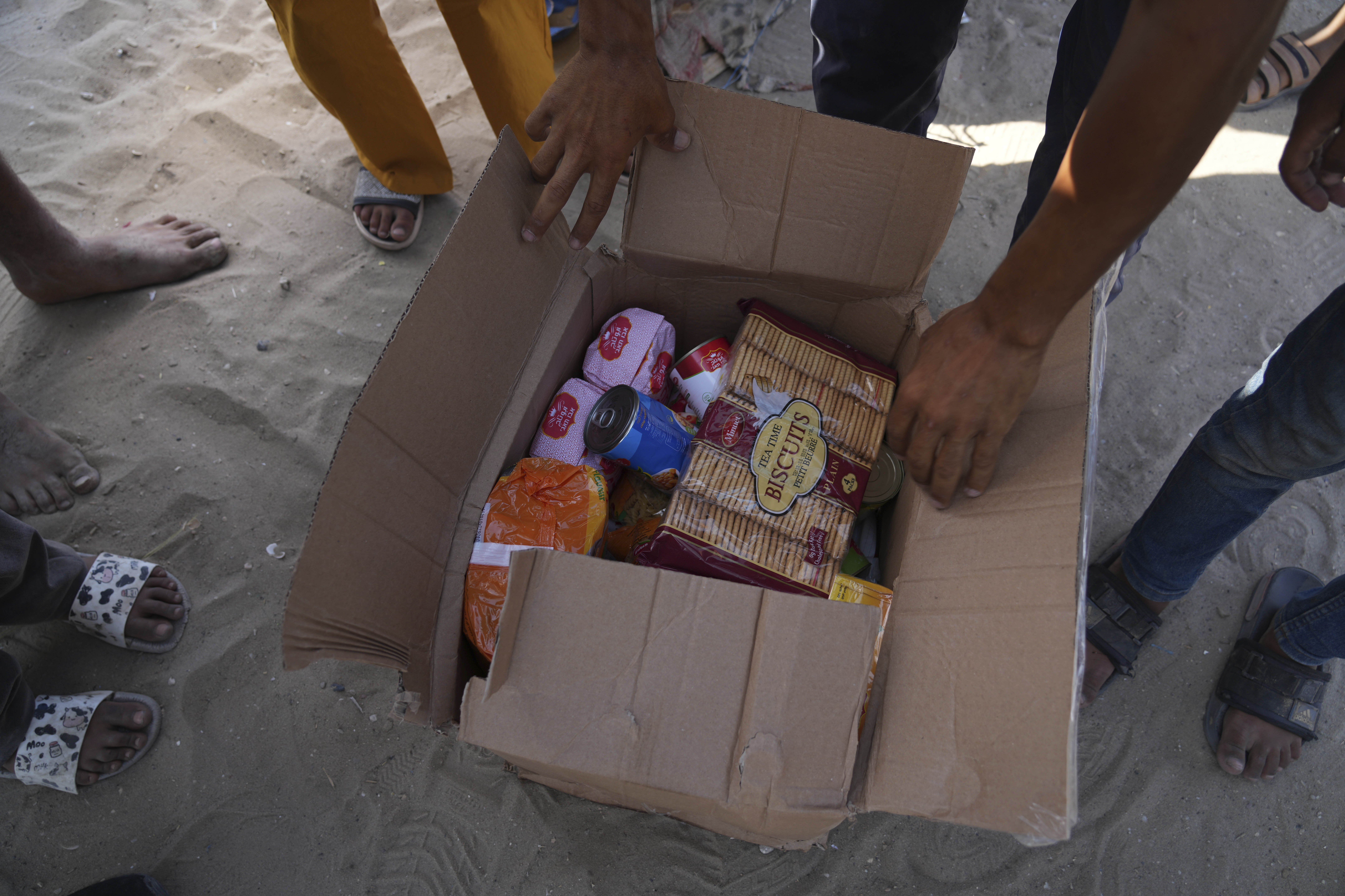 Palestinians open a box containing food and humanitarian aid packages delivered by the Gaza Humanitarian Foundation, a US-backed organisation approved by Israel, in Rafah, southern Gaza Strip, on Tuesday, May 27, 2025