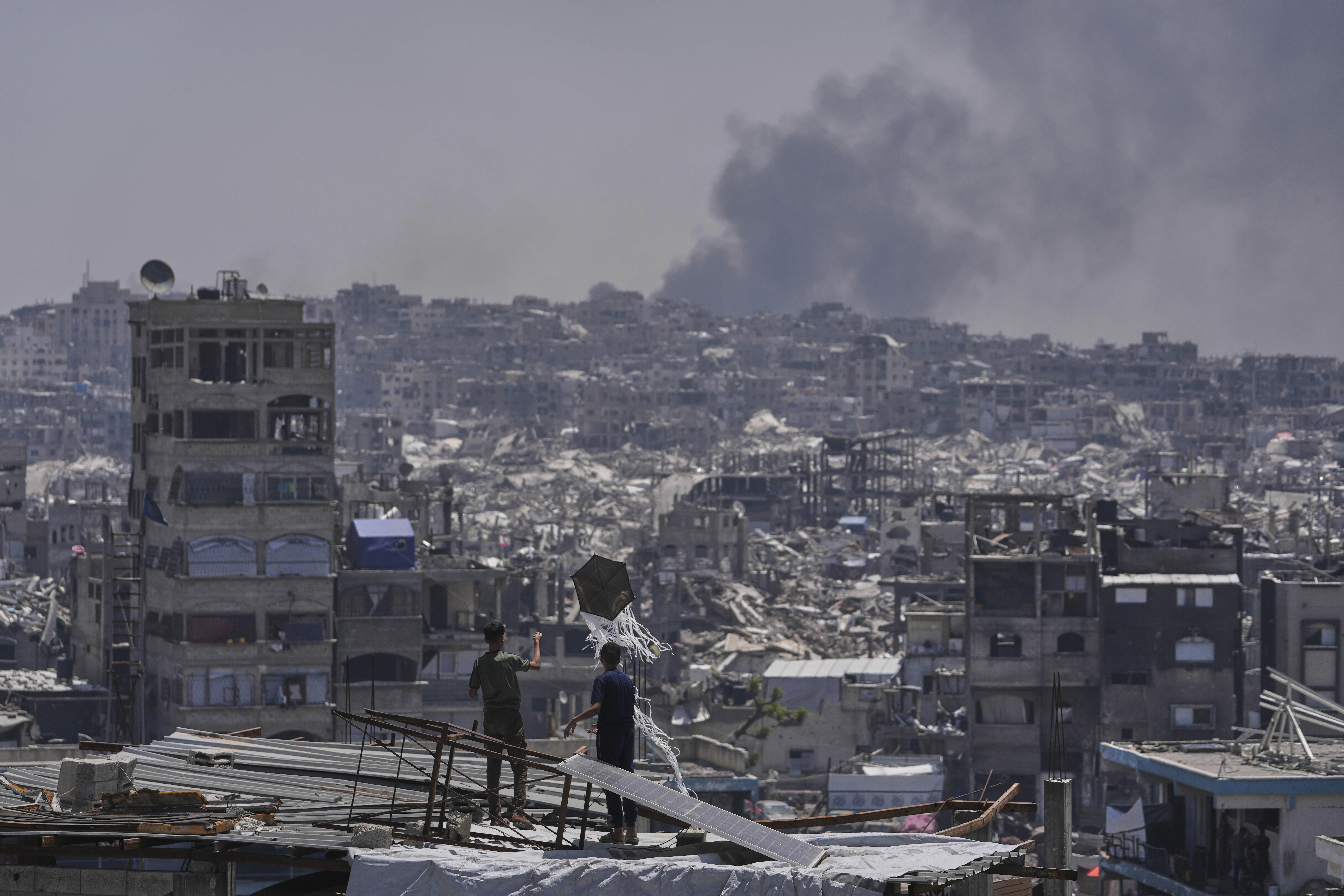 Palestinians look at smoke rises following an Israeli airstrike near Jabalia, northern Gaza Strip, Friday, May 16, 2025. (AP Photo/Jehad Alshrafi)