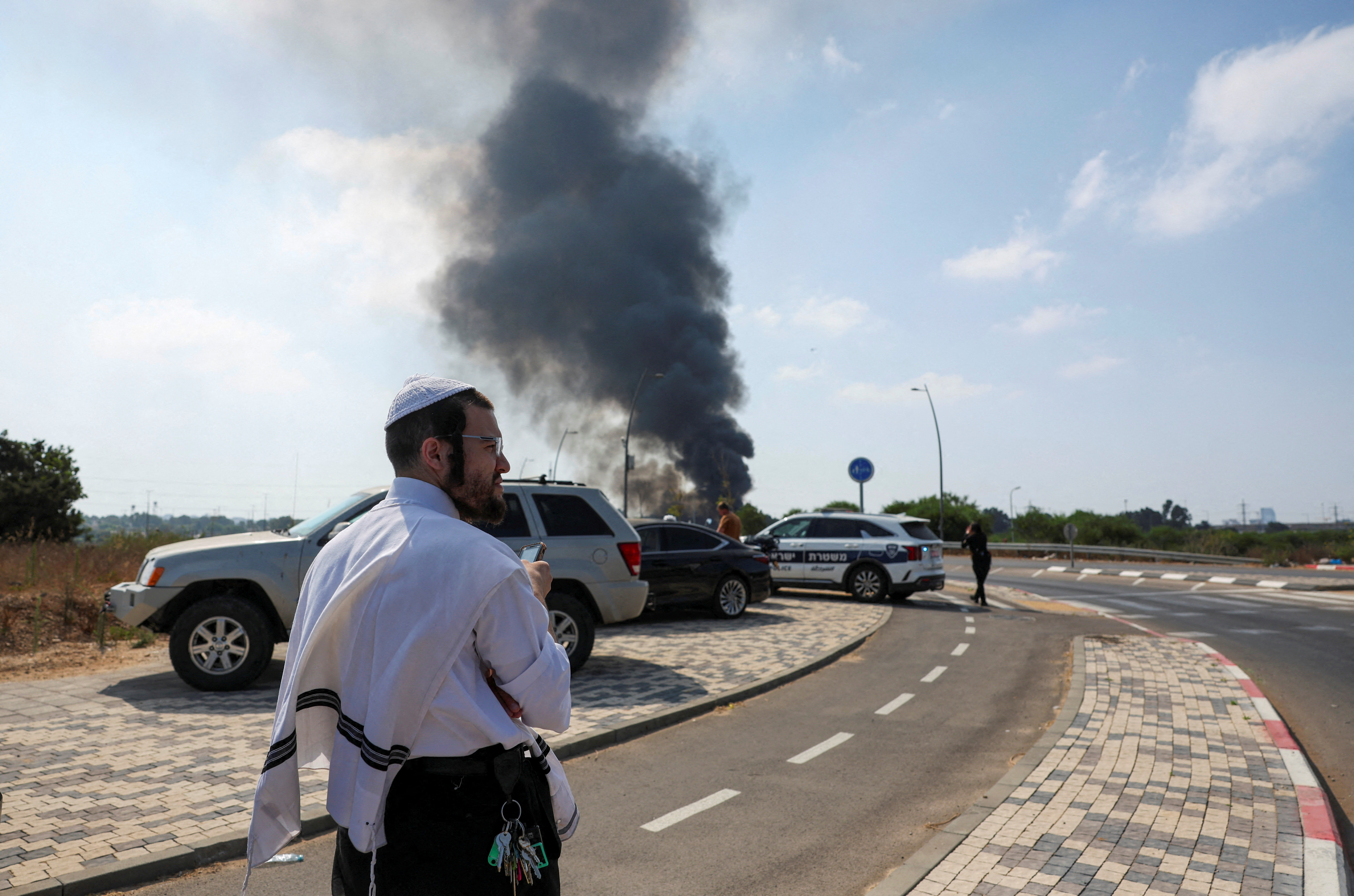 An Israeli man looks on, as smoke rises following a missile attack from Iran, in Herzliya, Israel, June 17, 2025. REUTERS/Ronen Zvulun TPX IMAGES OF THE DAY