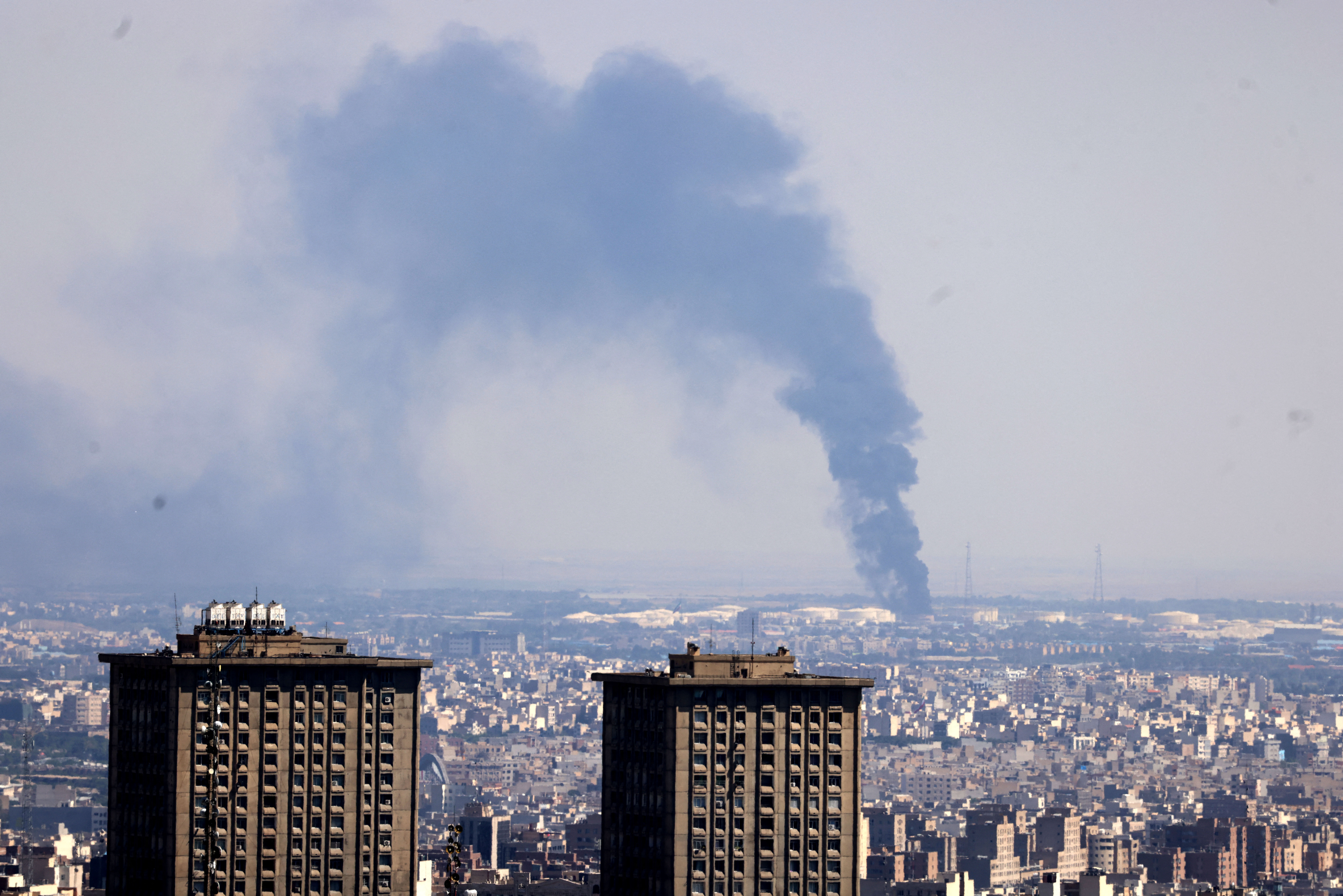 Smoke billows in the distance from an oil refinery following an Israeli strike on the Iranian capital Tehran on June 17, 2025