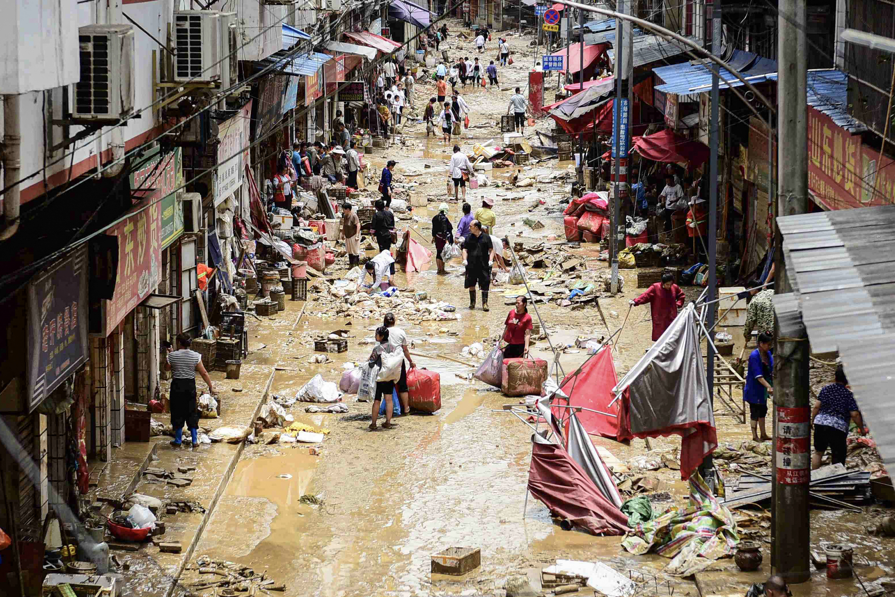 People walk with their belongings at a flood-affected area.