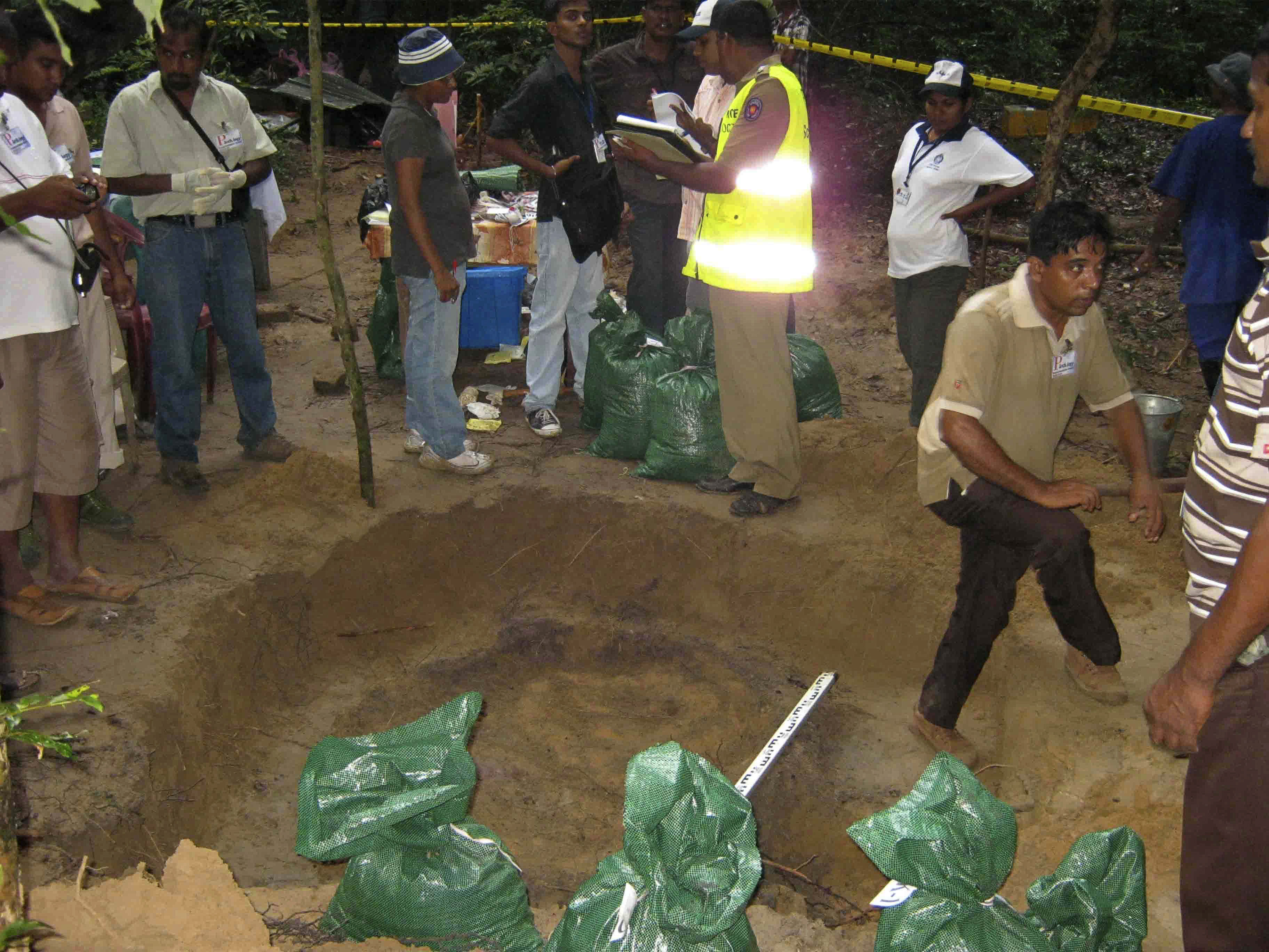 In this photo taken on Wednesday, Nov. 24, 2010, forensic experts and police officers investigate the mass grave found in a former rebel controlled area in Mullaitivu, Sri Lanka. Sri Lankan authorities on Tuesday began investigating an alleged mass grave that jailed rebel fighters say contains the ashes of 26 government troops executed during the country's civil war, a military spokesman said. (AP Photo/Sanath Priyantha)