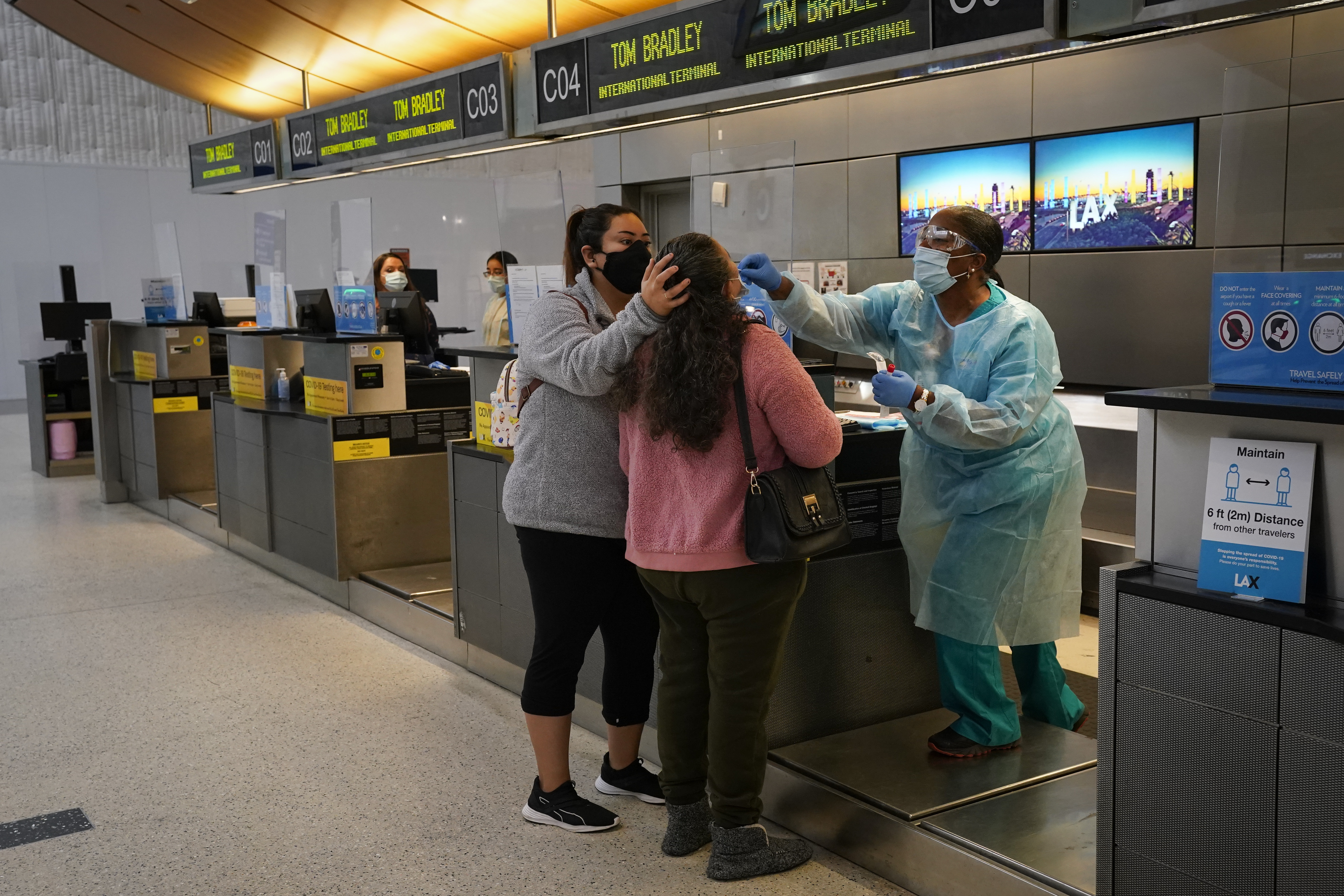 FILE - Licensed vocational nurse Caren Williams, left, collects a nasal swab sample from a traveler at a COVID-19 testing site at the Los Angeles International Airport in Los Angeles, Monday, Nov. 23, 2020.