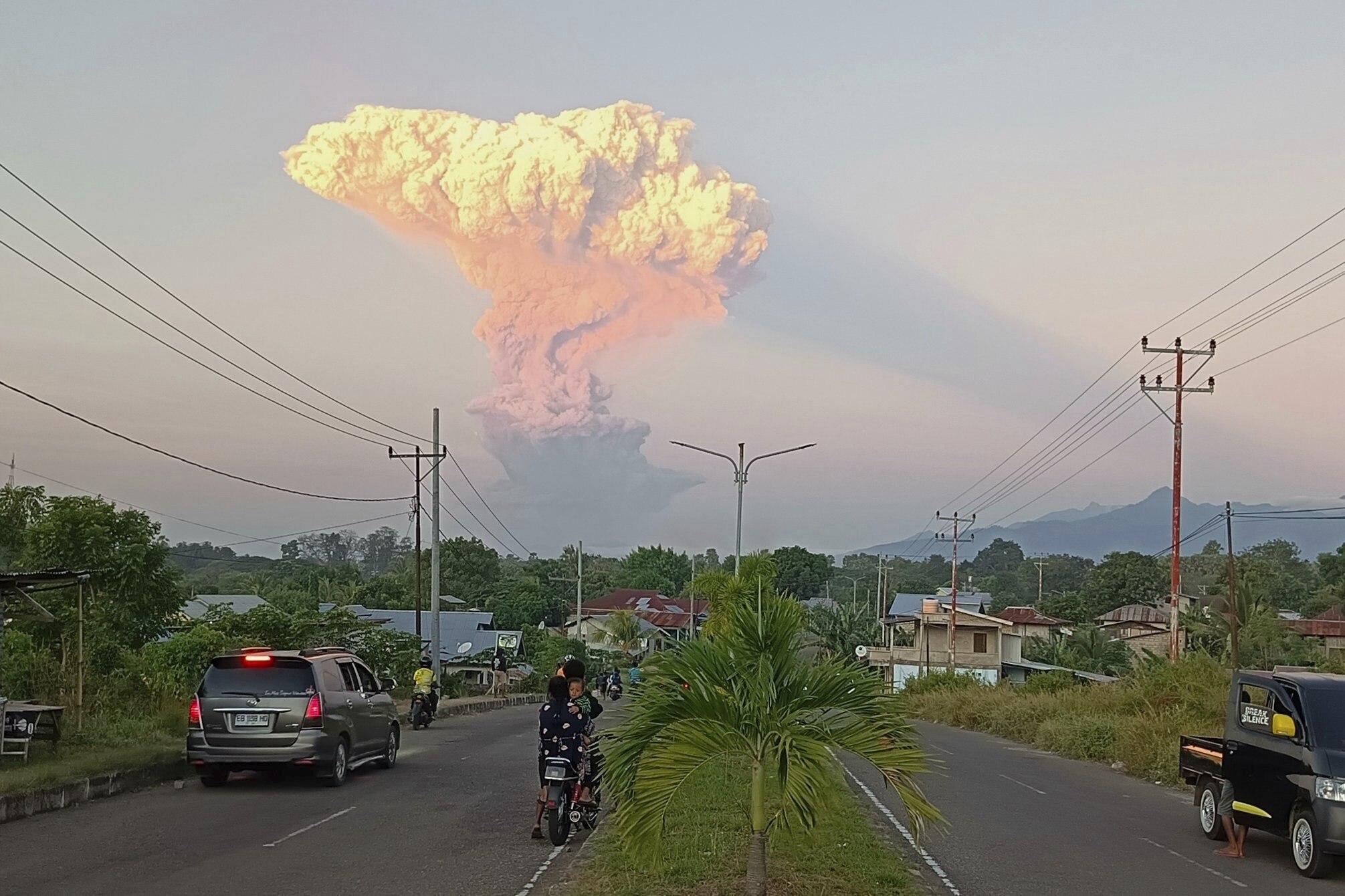 People watch as Mount Lewotobi Laki-Laki spews volcanic materials into the air during an eruption