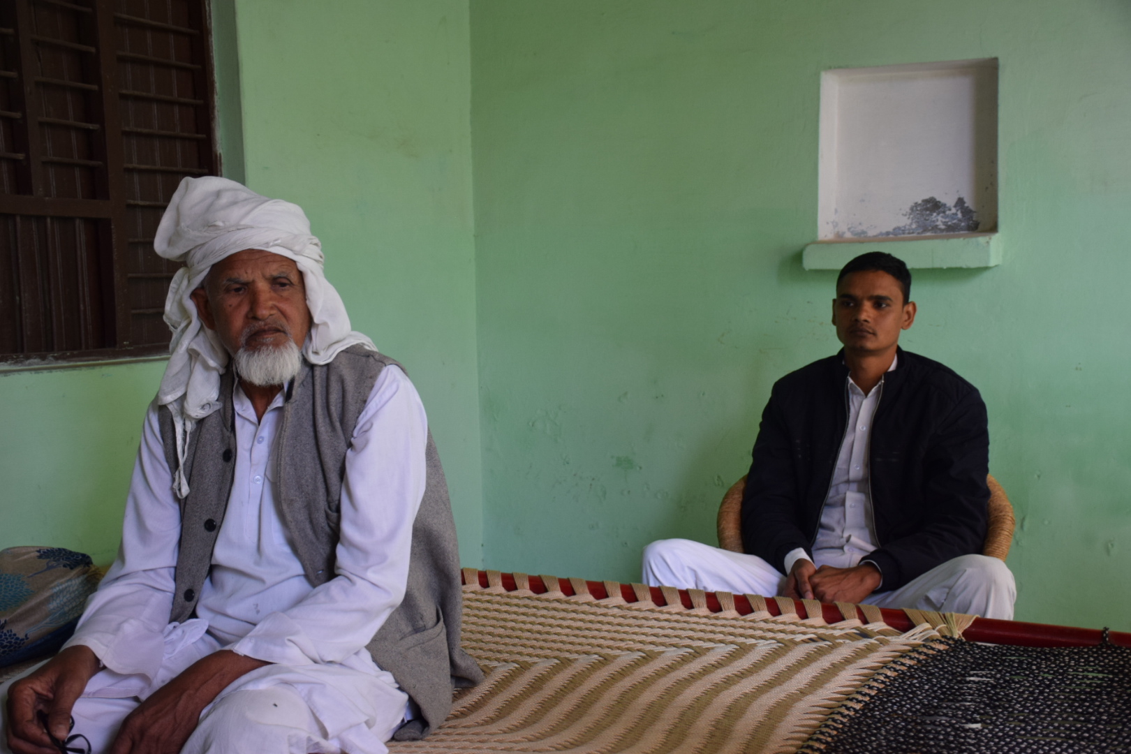 Mohsin (right) and his father in their home near Meerut, India, ponder over how they will repay a loan they took out on a credit scheme for farmers. Their loan was to pay off a dowry for Mohsin's sister [Ismat Ara/Al Jazeera]